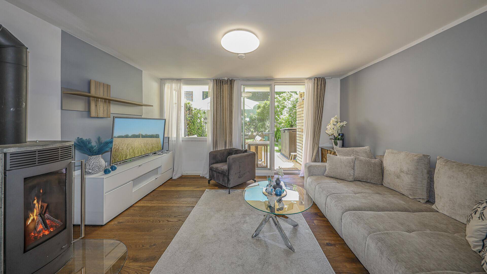 Helles Wohnzimmer mit Kamin, Holzboden und Zugang zur Terrasse.