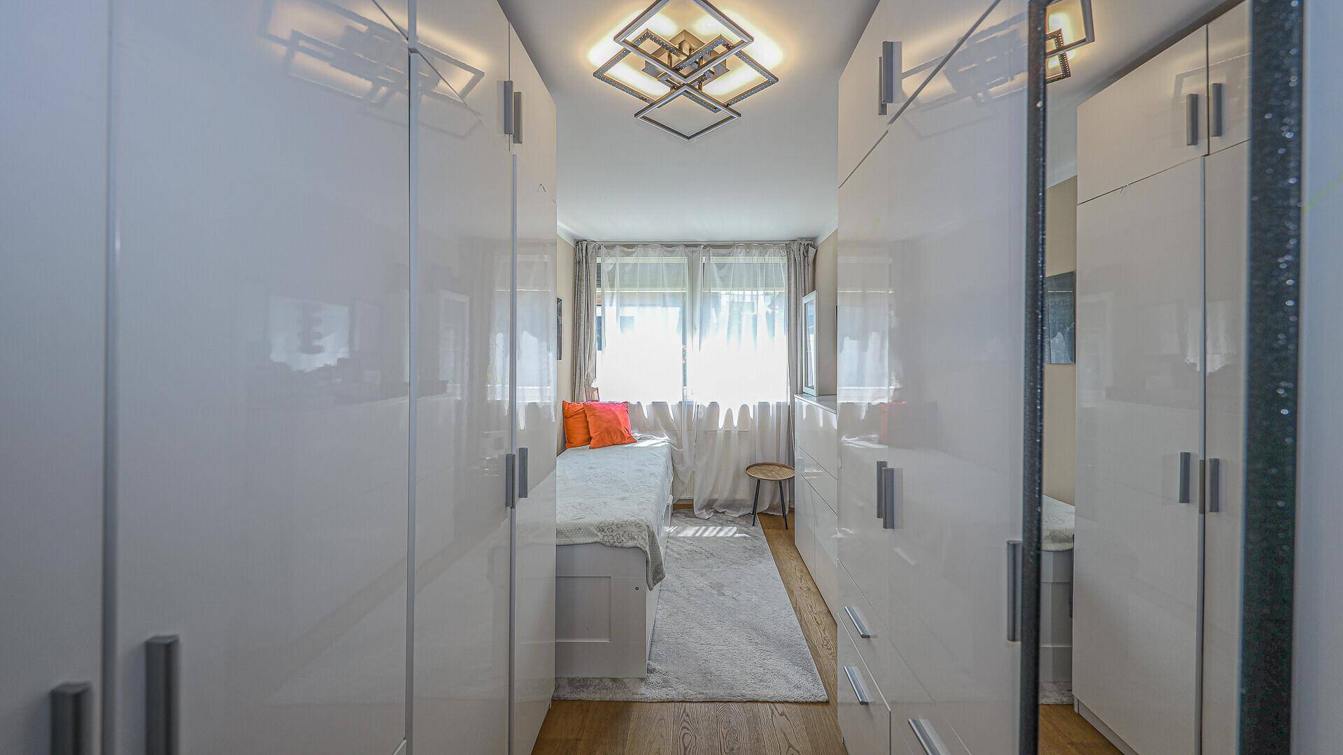 Helles Schlafzimmer mit Einbauschränken, Einzelbett und Fenster.