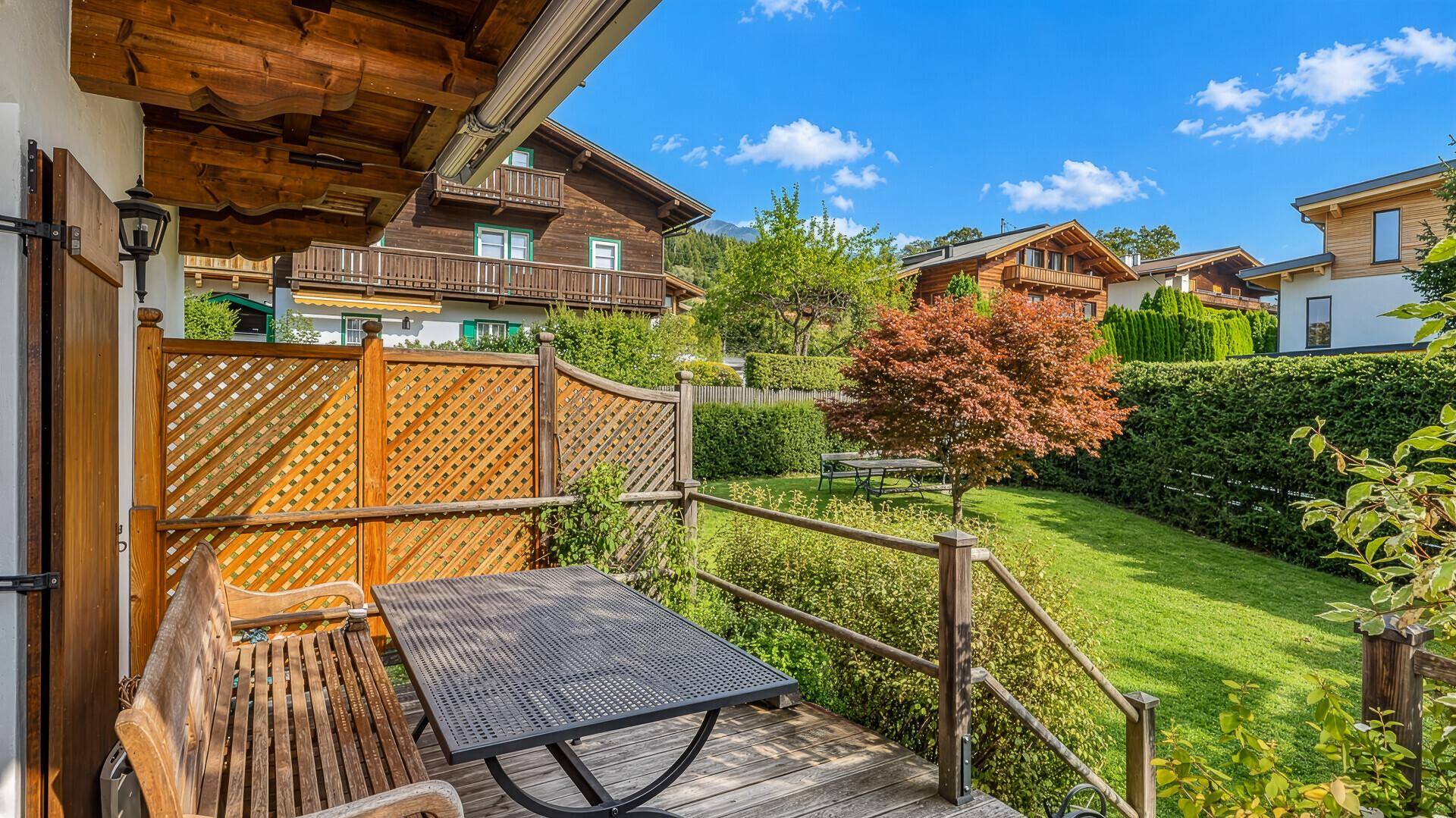 Gemütliche Terrasse mit Holzboden, Sitzgelegenheiten und Blick auf den Garten.