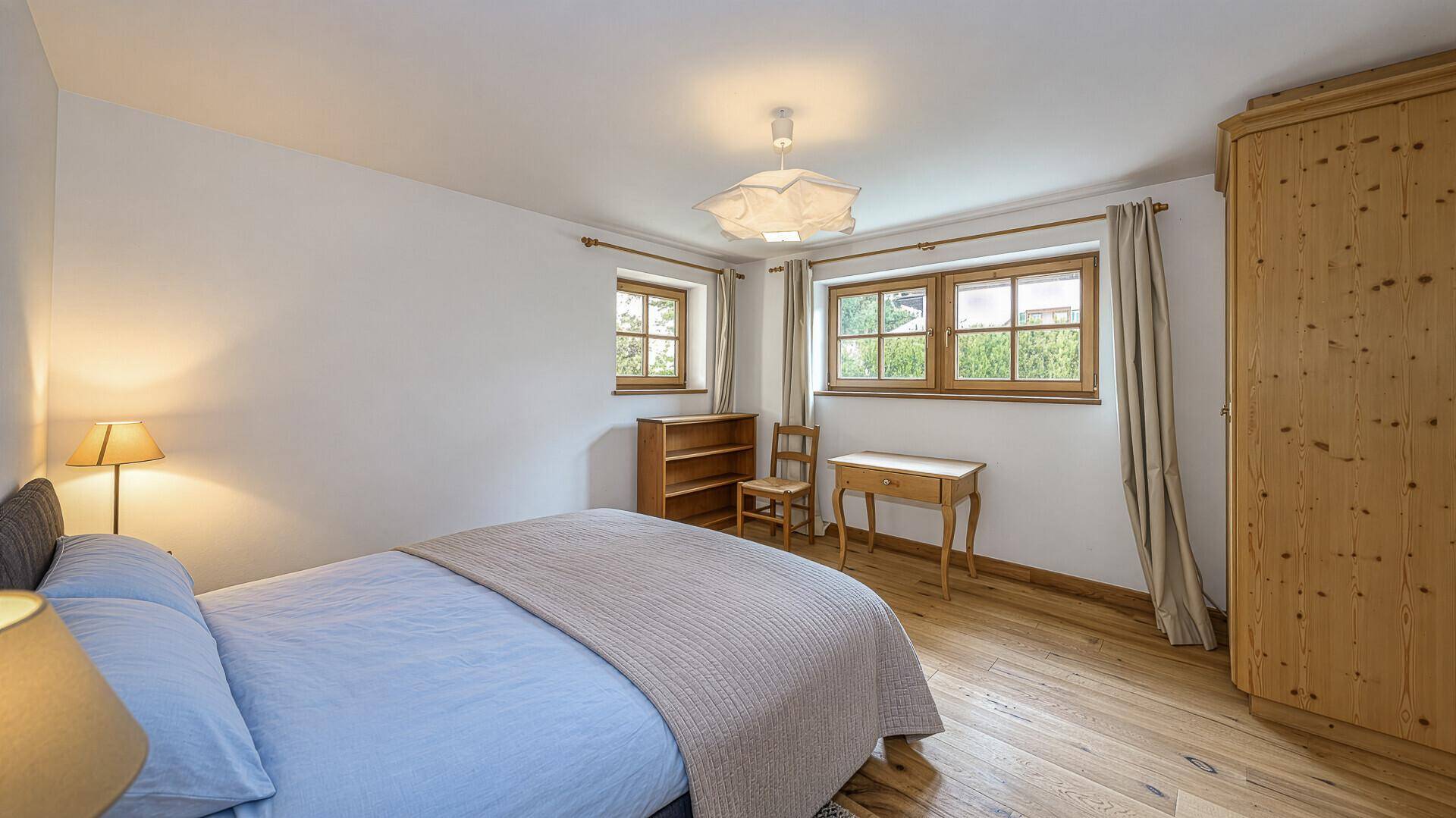 Ruhiges Schlafzimmer mit Holzboden, Doppelbett und Blick auf die Umgebung.