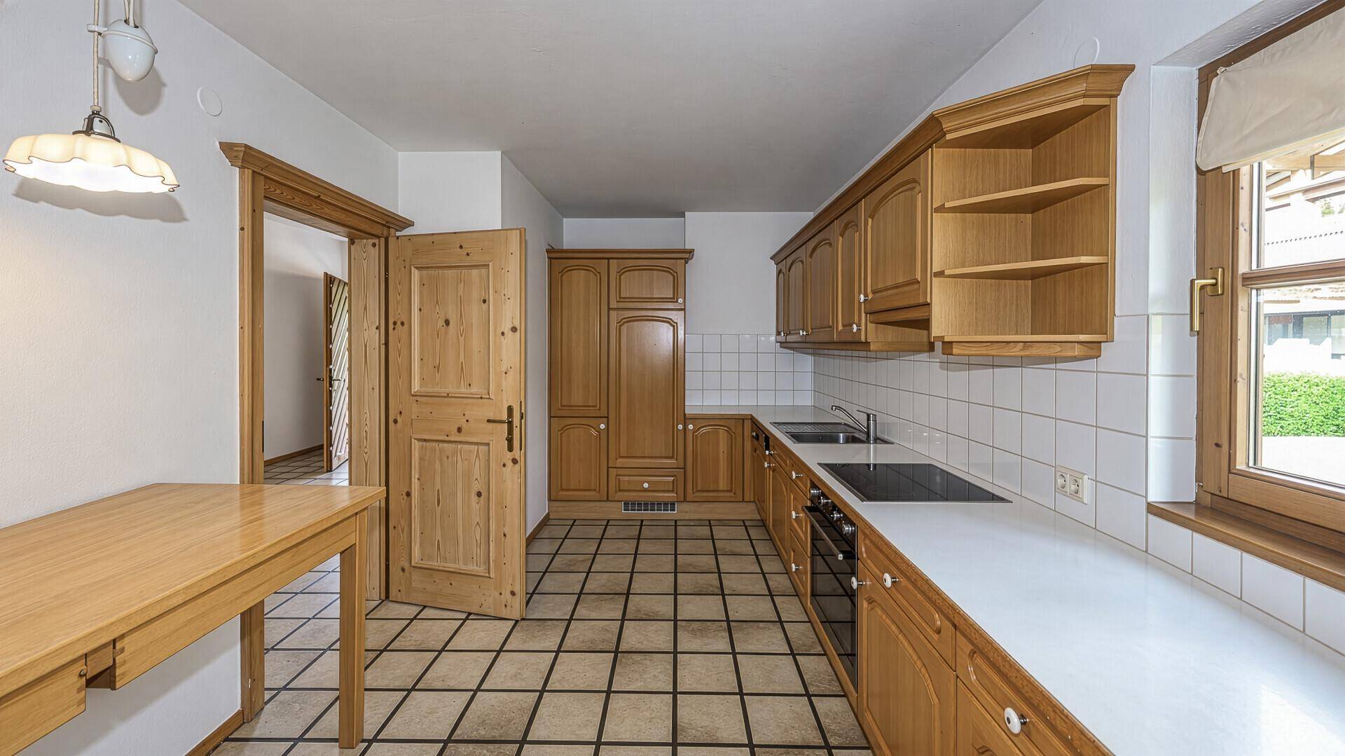 Traditionelle Küche mit Holzschränken, Fliesenboden und Essbereich.
