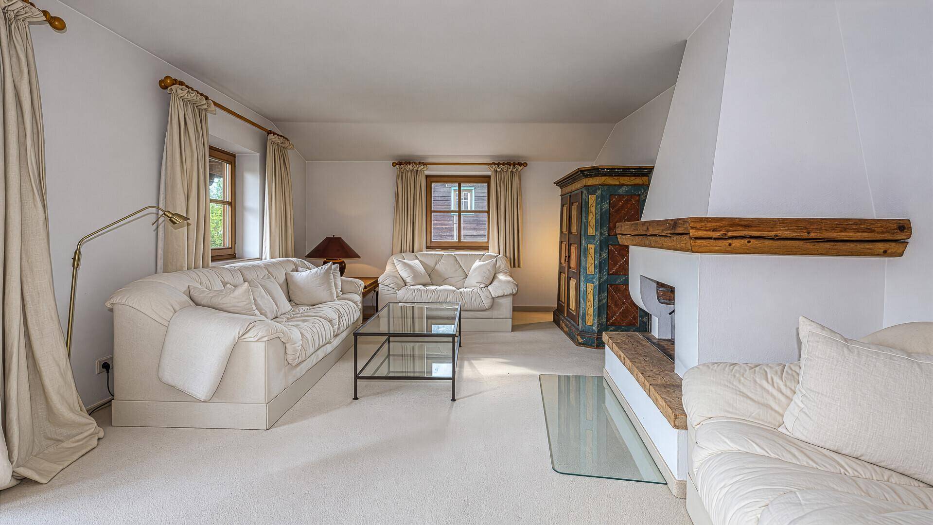 Gemütliches Wohnzimmer mit Kamin, hellen Sofas und Teppichboden.