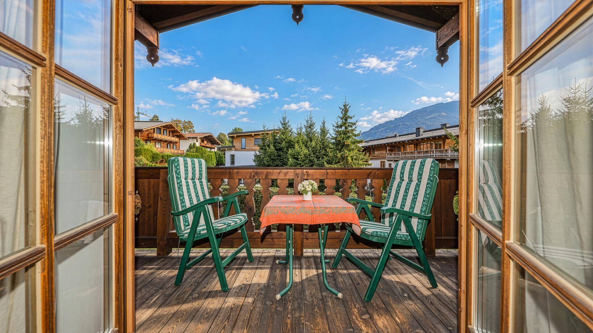 Sonniger Balkon mit Sitzgelegenheiten und Blick auf die umliegende Berglandschaft.