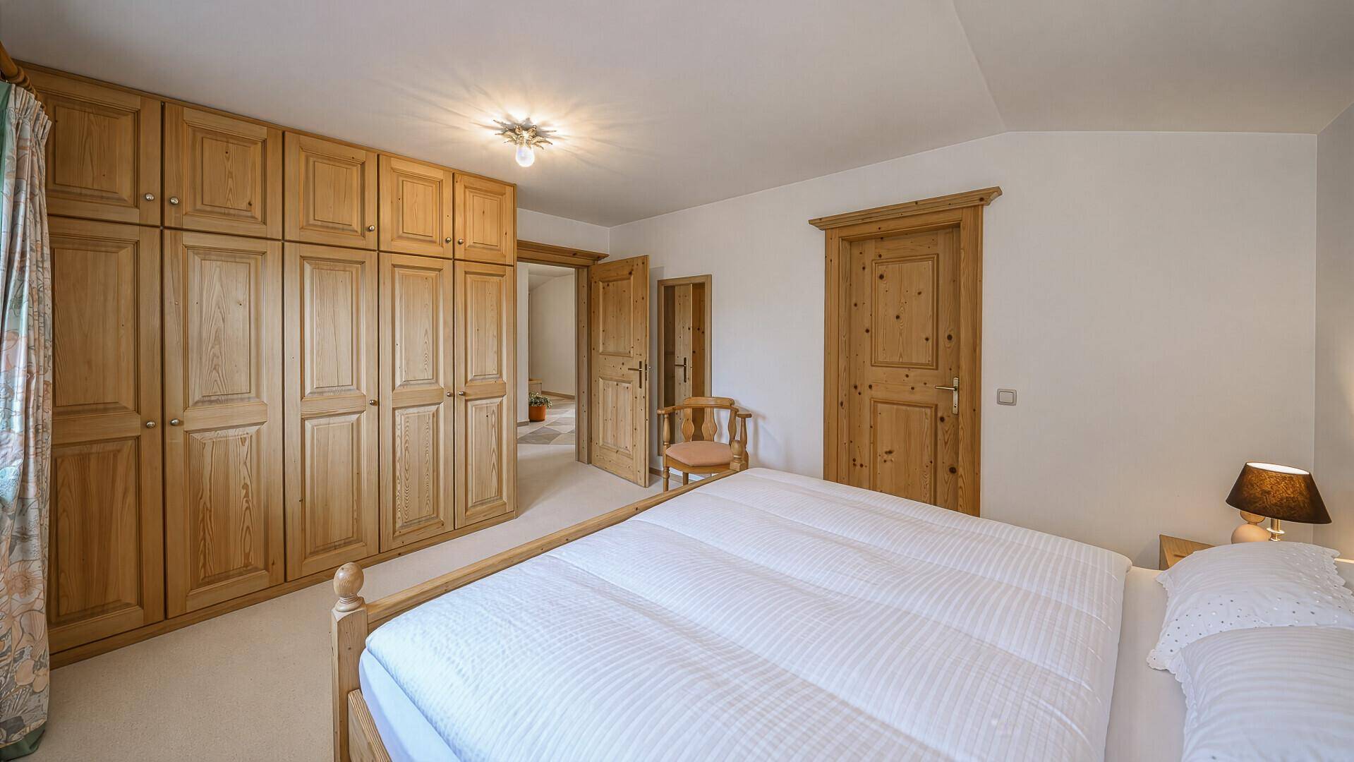 Geräumiges Schlafzimmer mit Einbauschränken aus Holz und Doppelbett.