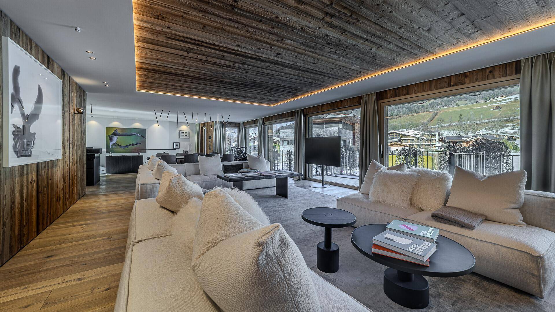 Heller Wohnbereich mit bequemen Sofas, Holzwänden und Deckenpaneelen sowie Panoramablick.