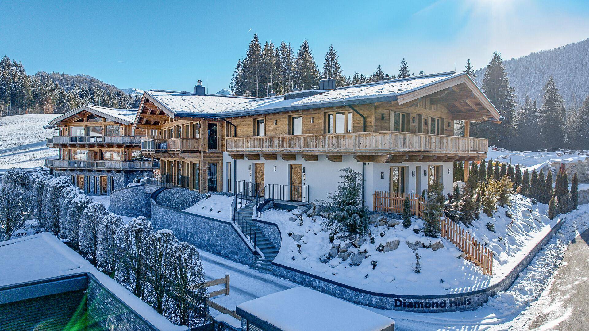 Luxuriöses Chalet-Anwesen in verschneiter Berglandschaft mit mehreren Balkonen und Terrassen.