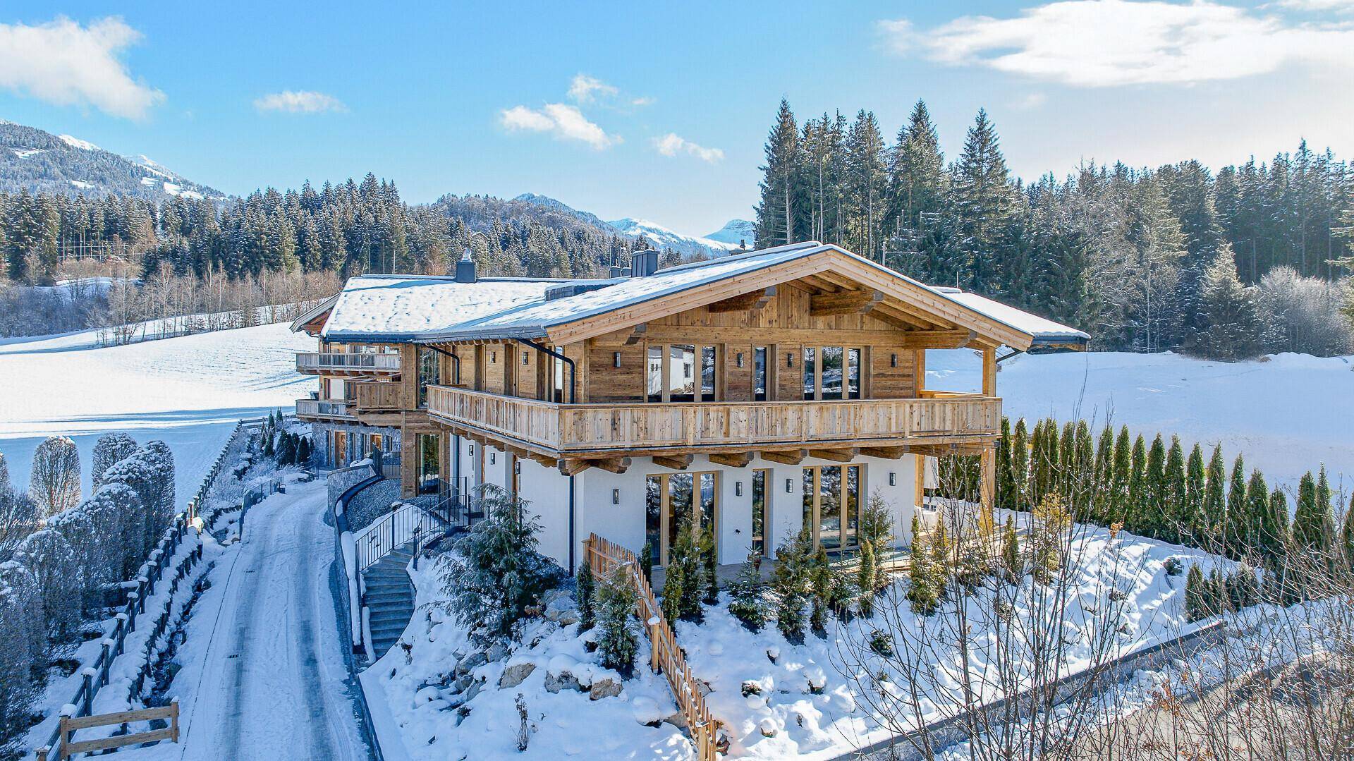 Elegantes Chalet mit Holzfassade und Balkonen, eingebettet in eine idyllische Winterlandschaft.
