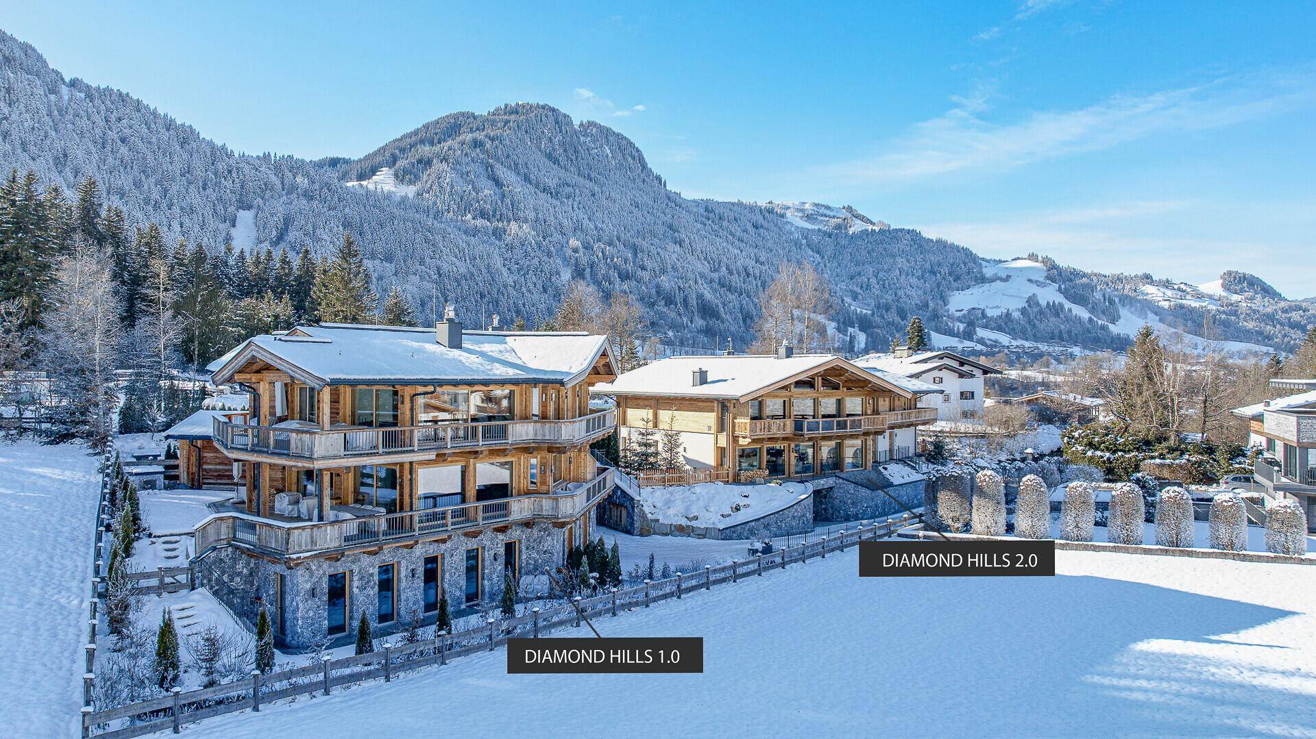 Zwei luxuriöse Chalets in verschneiter Berglandschaft mit moderner Architektur und großzügigen Balkonen.