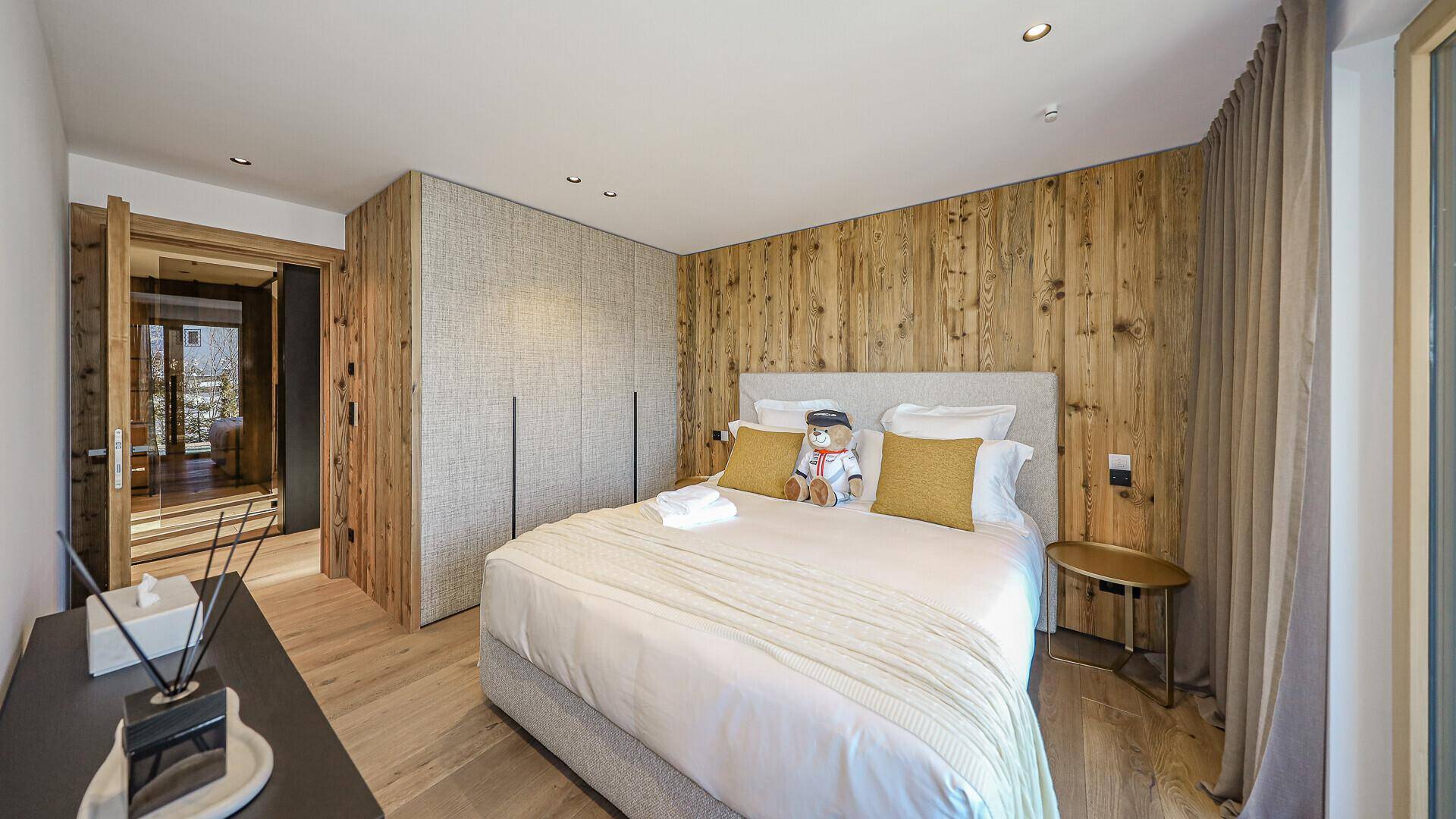 Gemütliches Schlafzimmer mit Holzboden, Holzwand und integrierten Schränken in modernem Design.