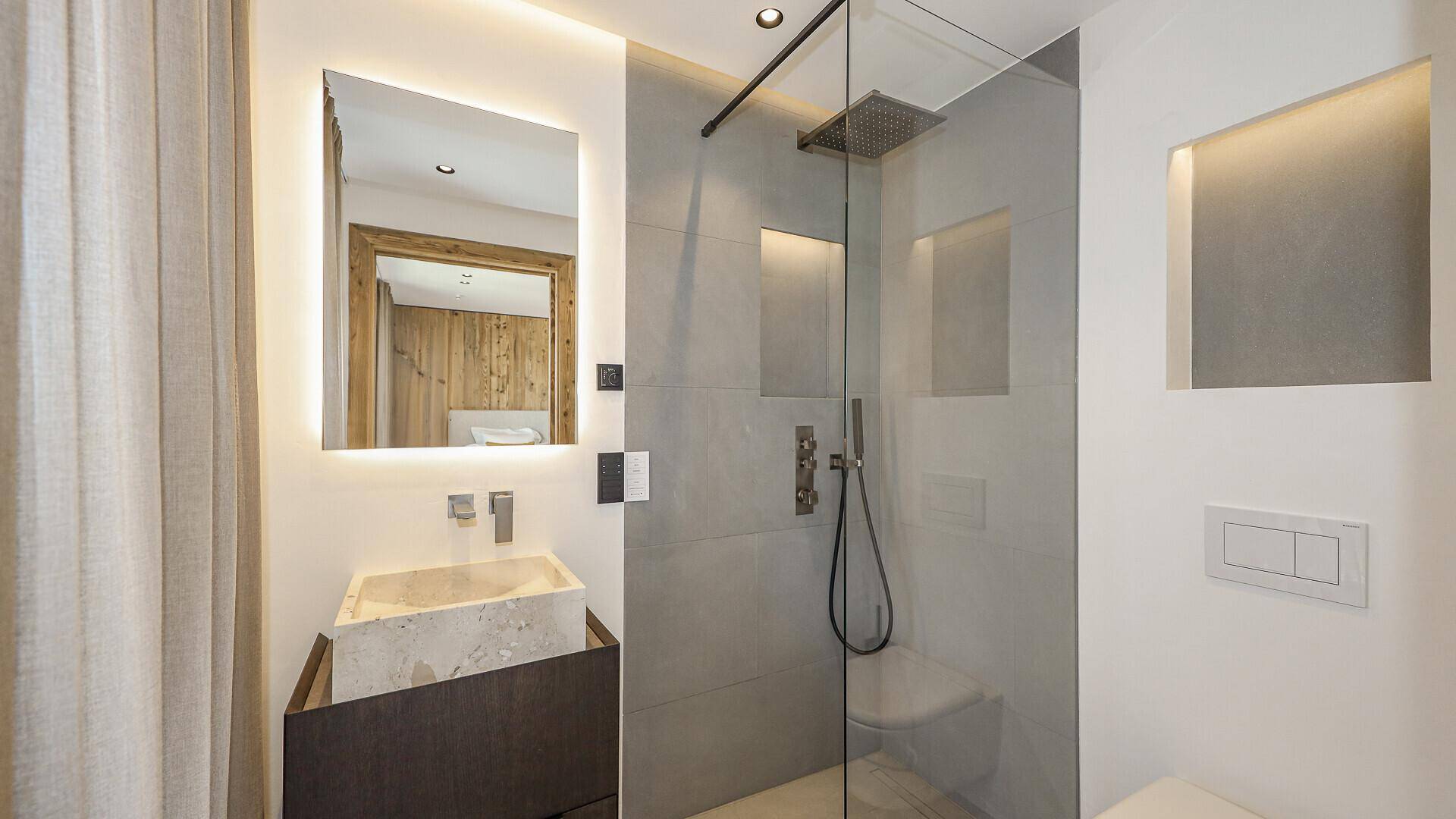 Modernes Badezimmer mit begehbarer Dusche, Einzelwaschbecken und beleuchtetem Spiegelschrank.