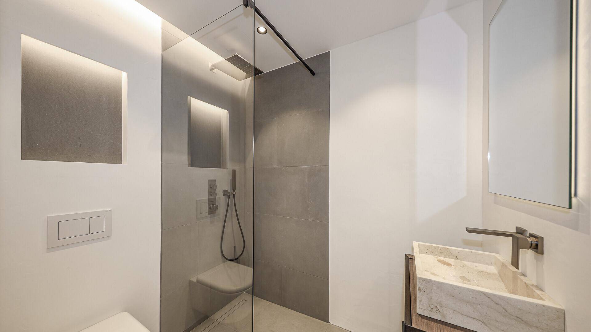 Modernes Badezimmer mit begehbarer Dusche, Einzelwaschbecken und minimalistischem Design.