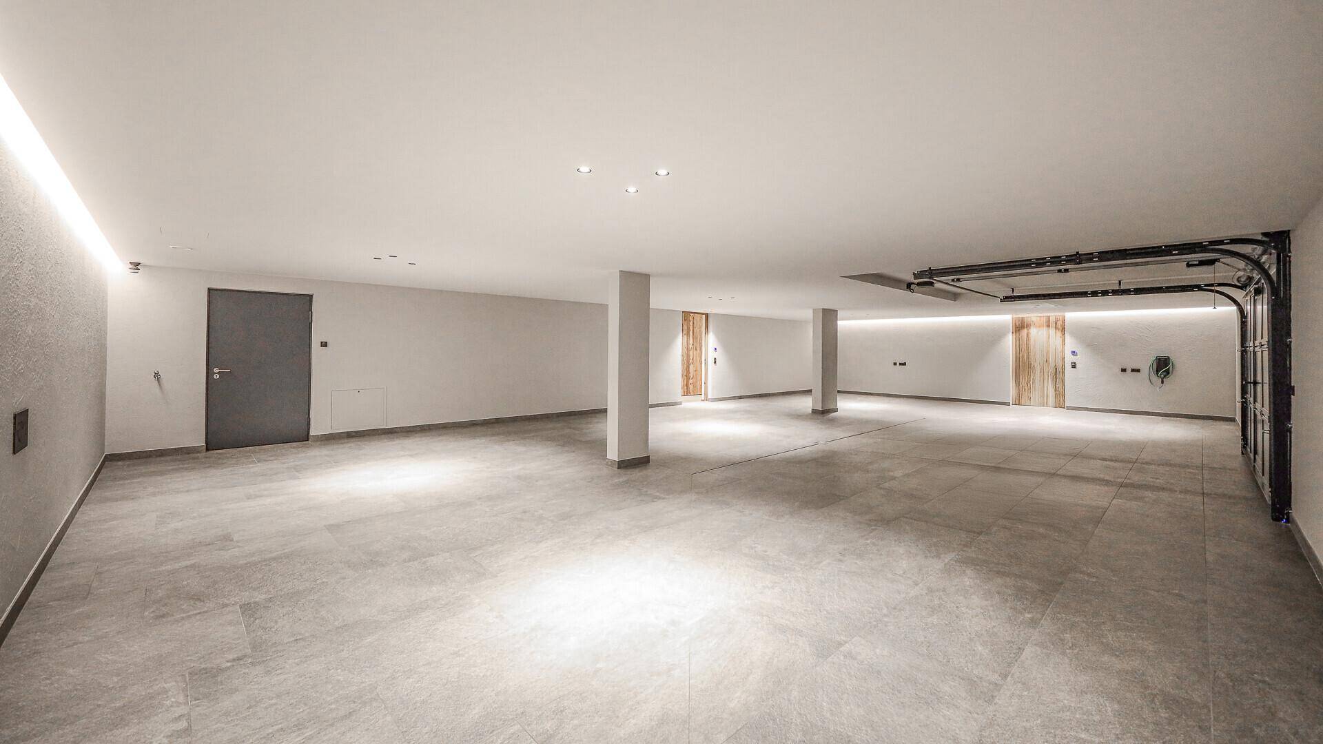 Geräumige und helle Tiefgarage mit glattem Betonboden und modernen Rolltoren.