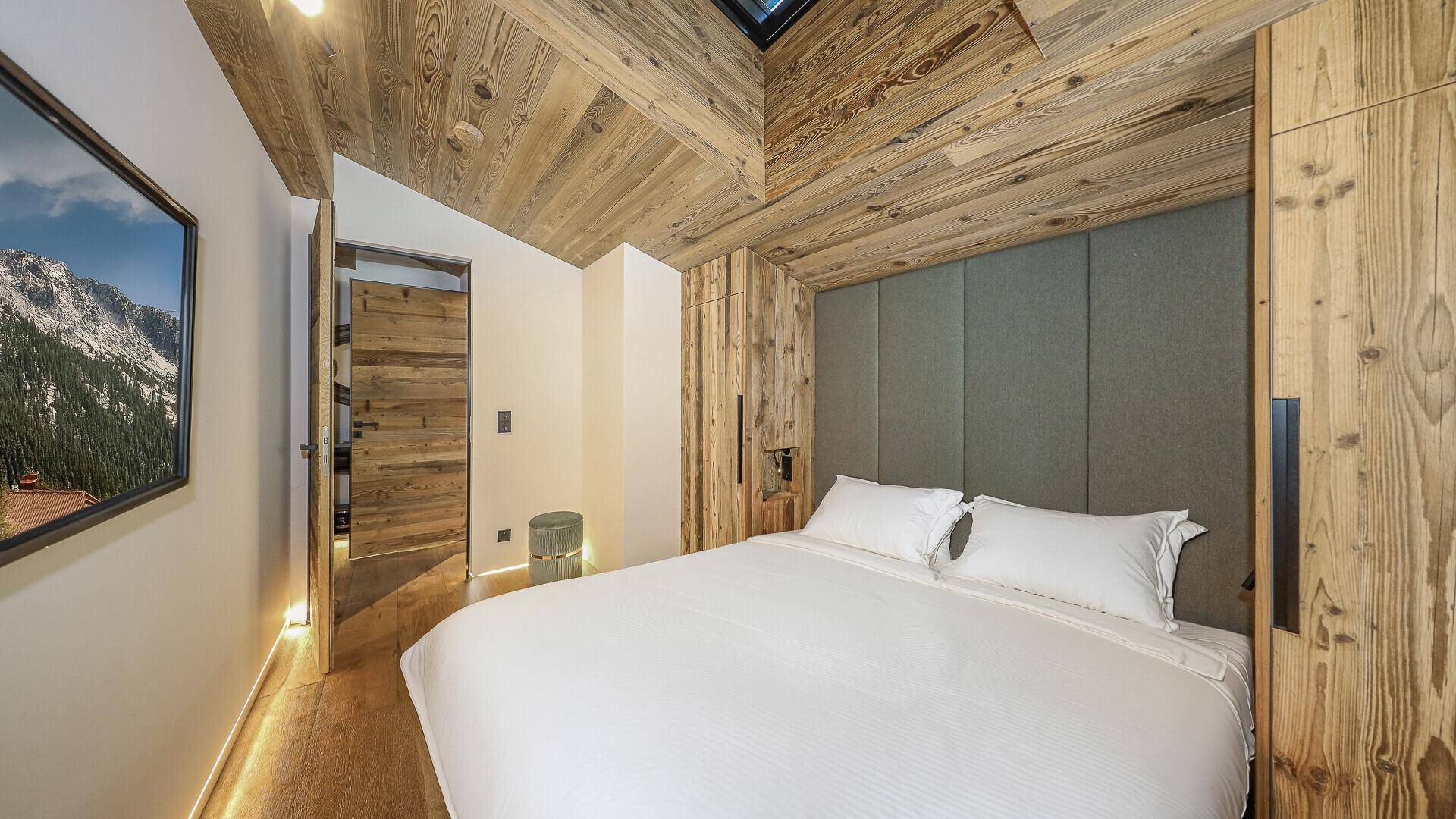 Gemütliches Schlafzimmer mit Holzbalkendecke, Einbauschränken und Blick auf die Berge.
