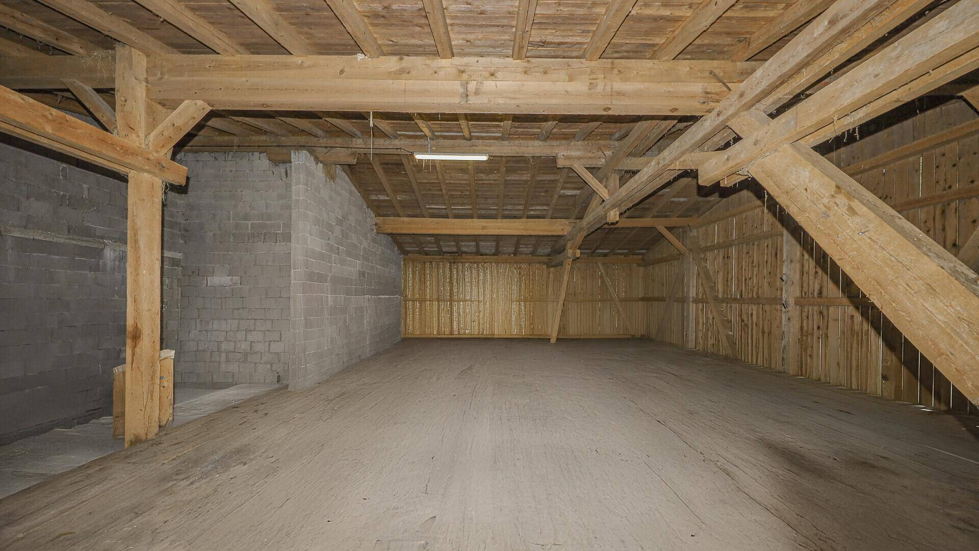 Geräumiger Lagerraum mit sichtbaren Holzbalken und Holzverkleidung.