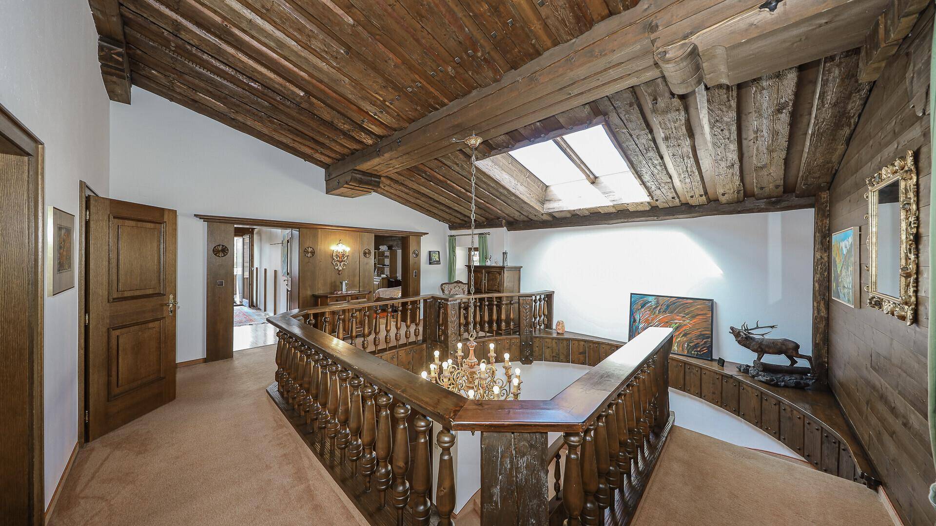 Heller Galeriebereich im Obergeschoss mit Holzgeländer, Holzbalkendecke und Dachfenster.
