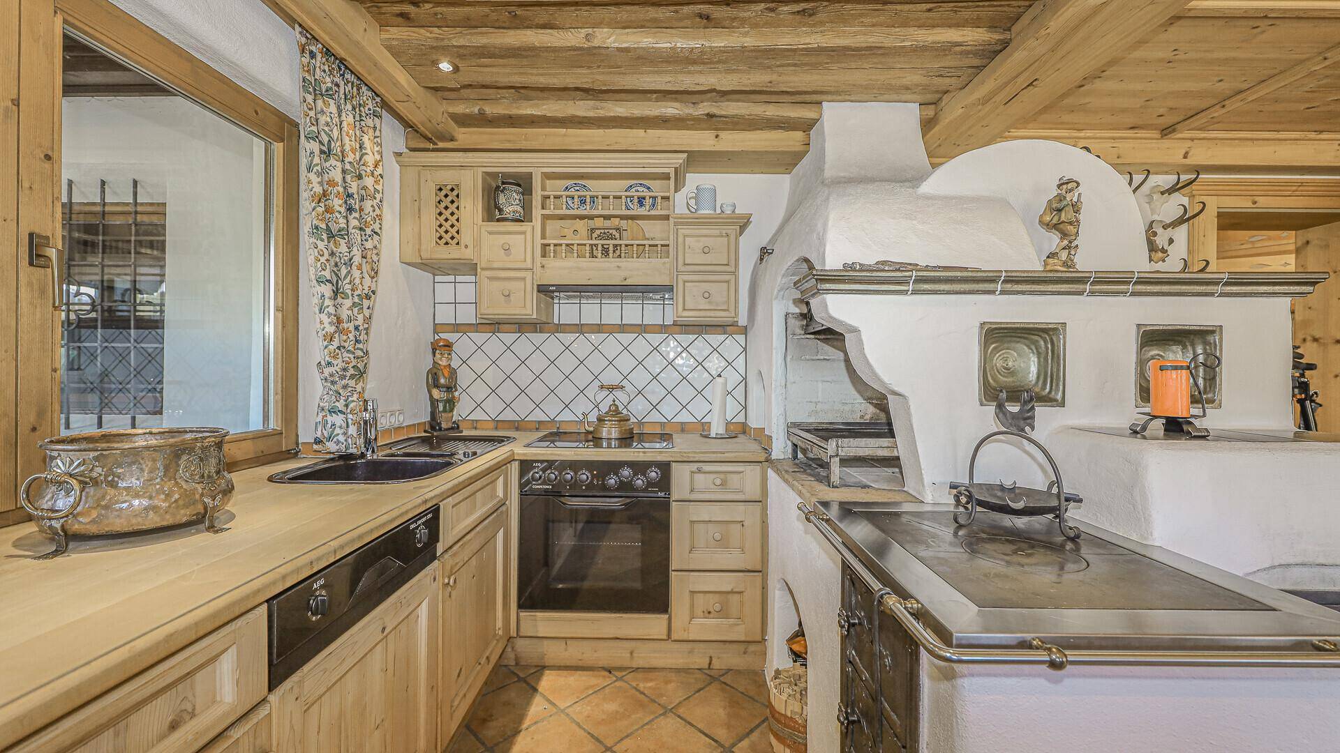 Traditionelle Küche mit Kachelofen, Holzschränken und rustikalen Details.