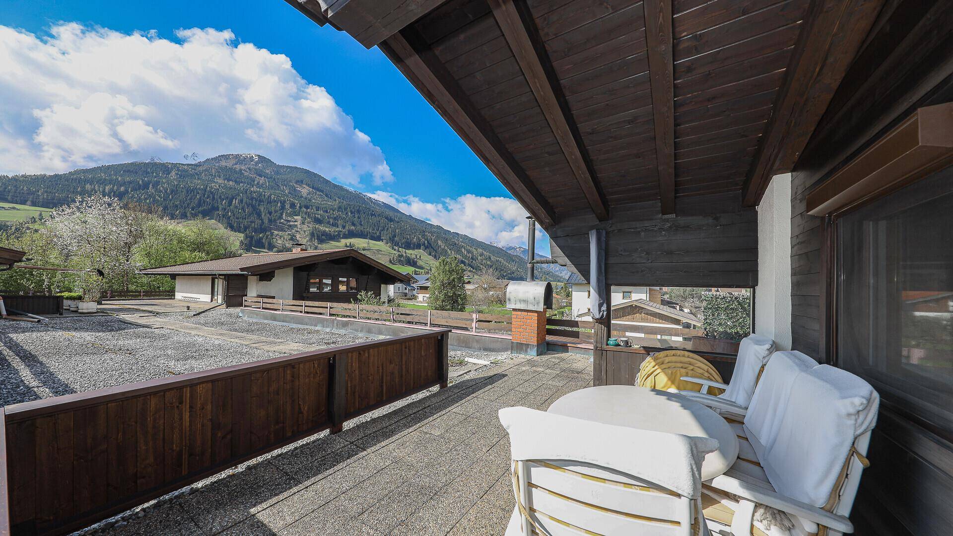 Geräumiger Balkon mit Sitzgelegenheiten und weitem Blick auf die umliegende Bergwelt.