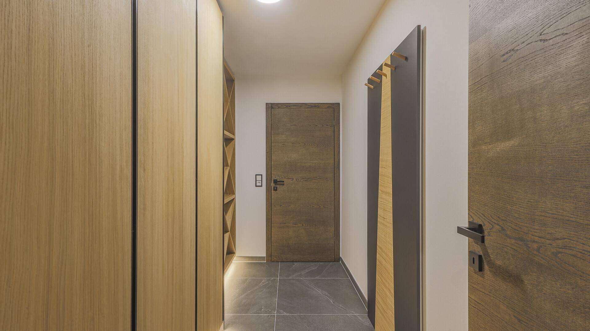 Heller Flur mit Einbauschränken, Holzdetails und Fliesenboden.
