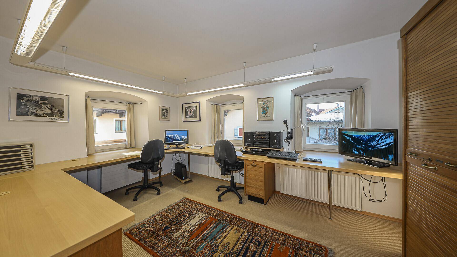 Geräumiges Büro mit mehreren Arbeitsplätzen, Teppichboden und Fenstern.