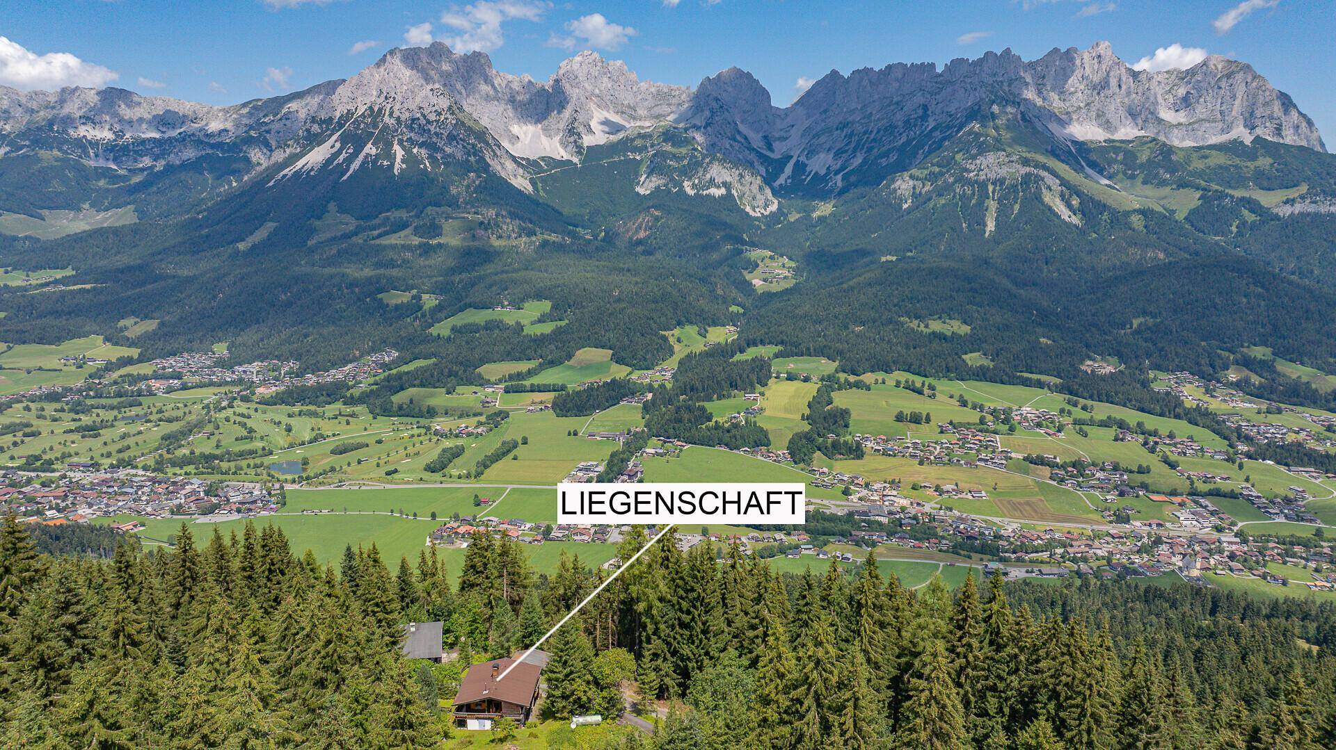 Luftaufnahme der Liegenschaft in einer malerischen Berglandschaft mit umliegendem Dorf.