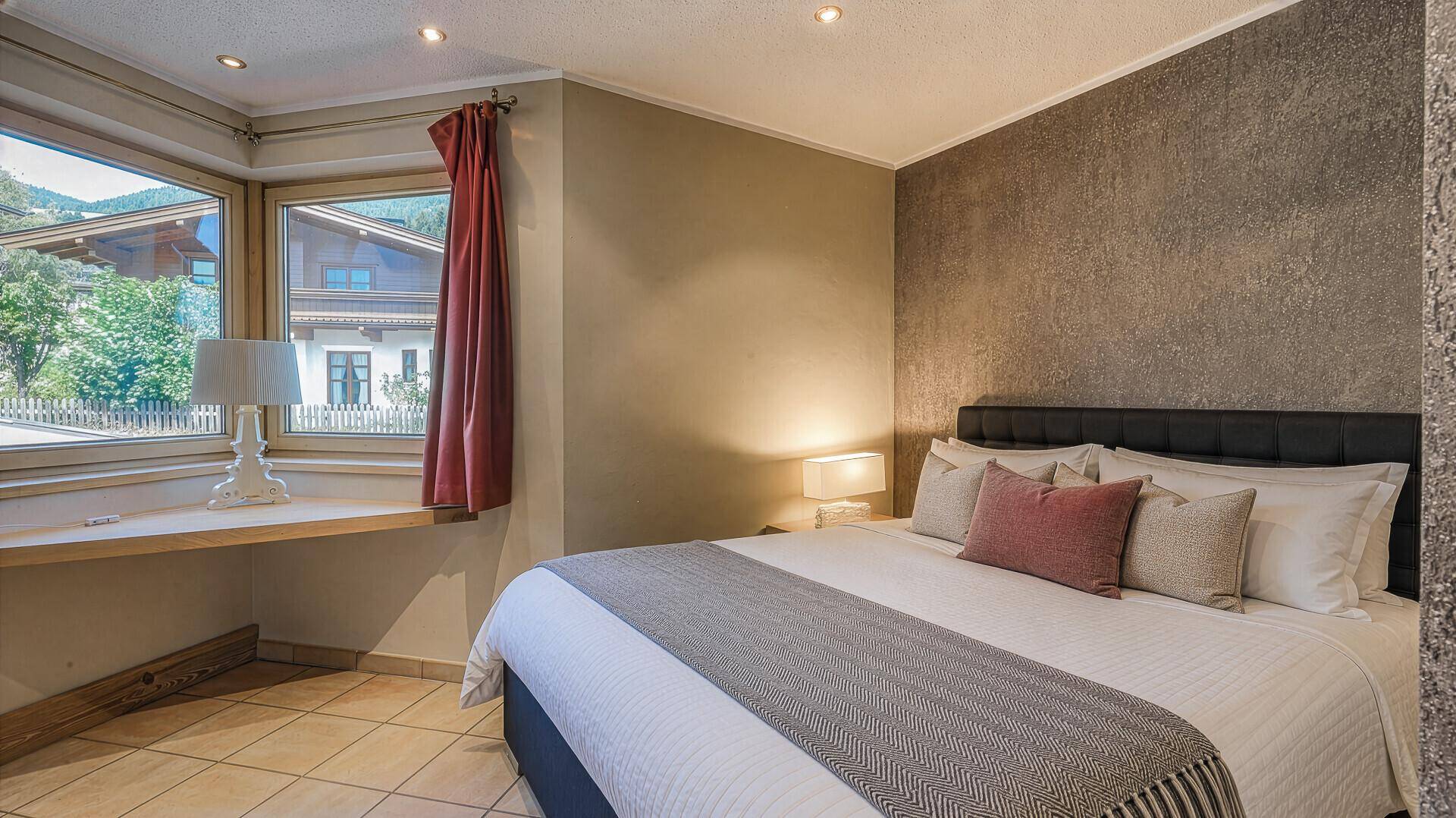Komfortables Schlafzimmer mit Doppelbett und Erkerfenstern, die viel Tageslicht hereinlassen.