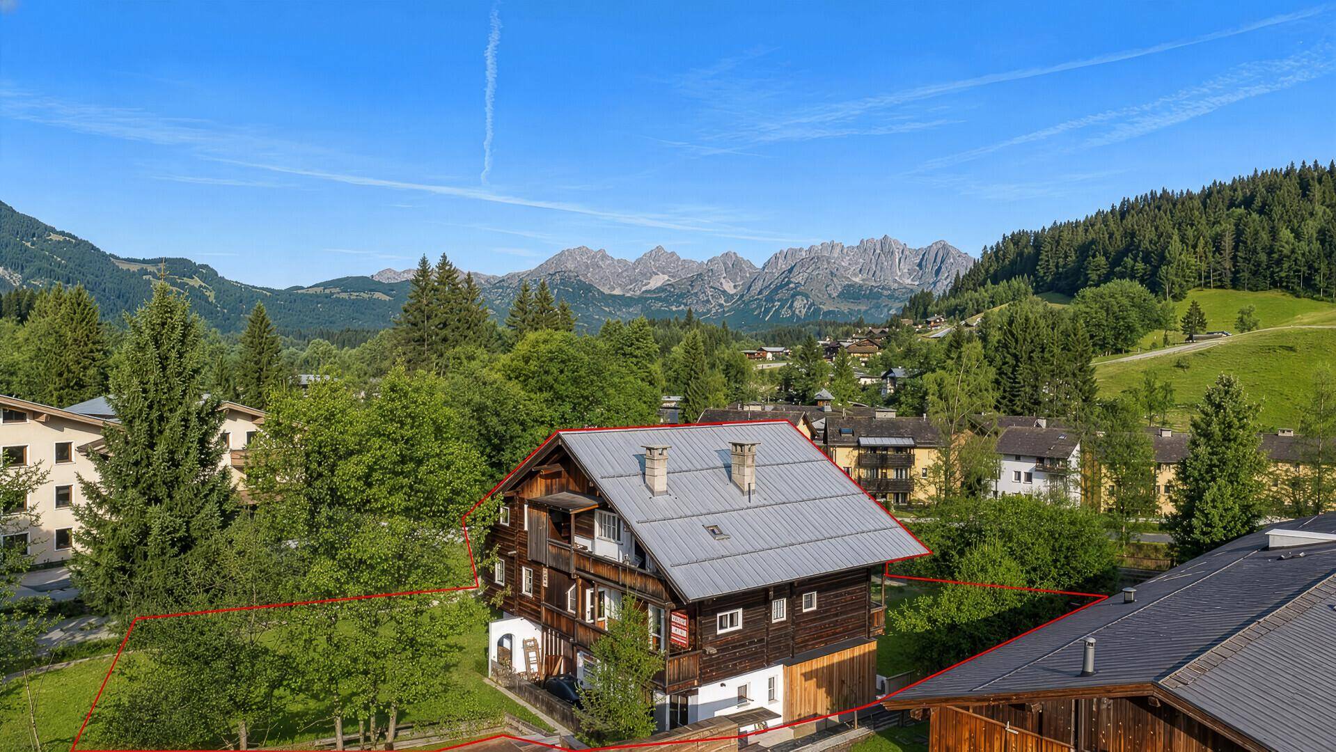 Luftaufnahme eines Neubauprojekts in einer grünen Berglandschaft mit umliegenden Gebäuden.