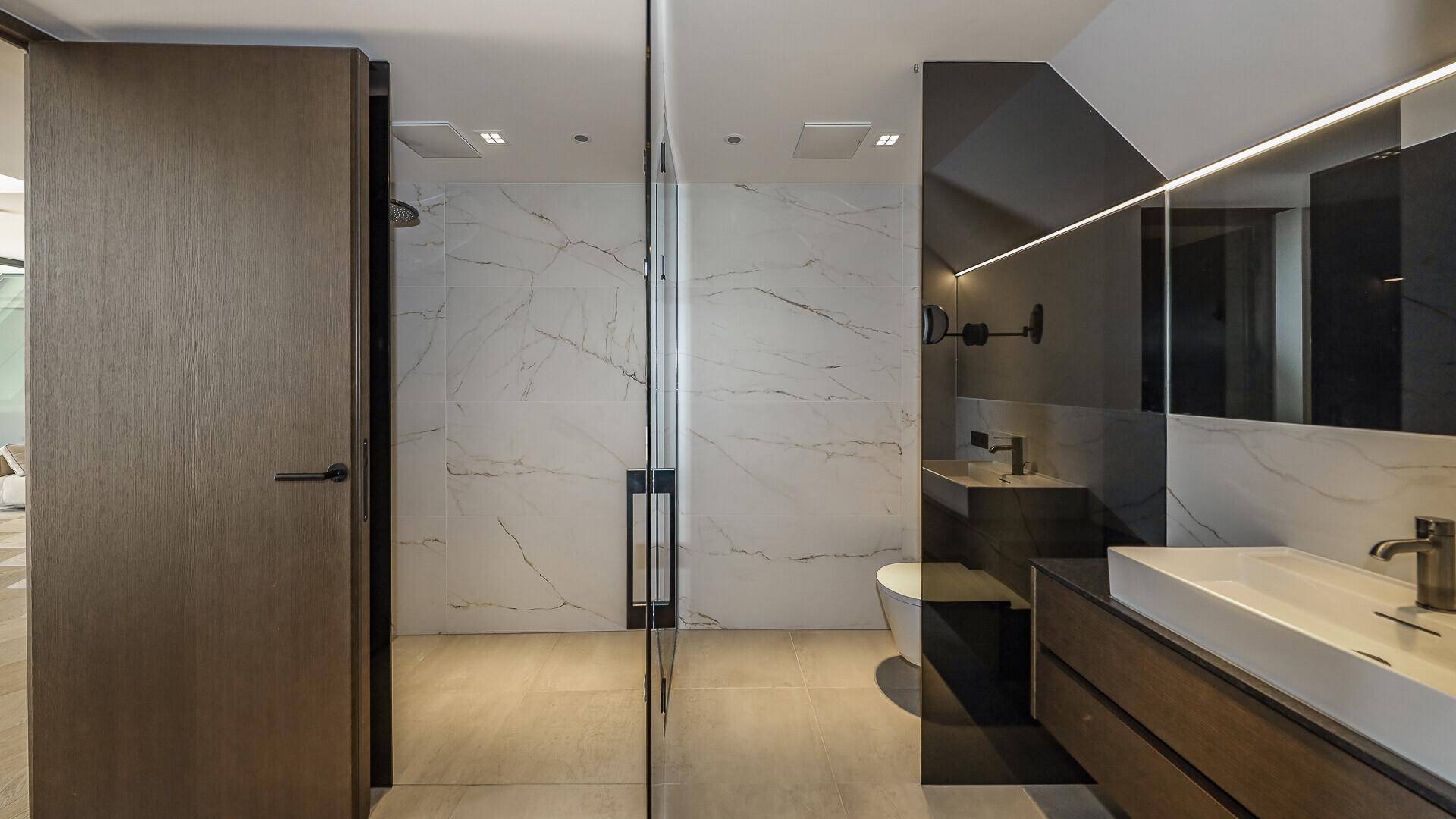Modernes Badezimmer mit begehbarer Dusche, Wand-WC und eleganten Marmorfliesen.
