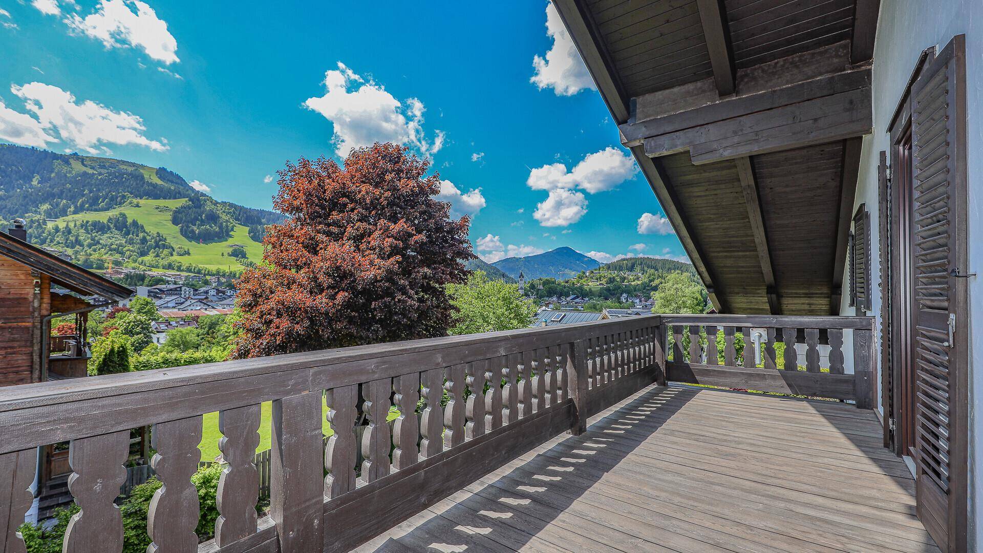 Geräumiger Holzbalkon mit traditionellem Geländer und Panoramablick auf die umliegende Berglandschaft.