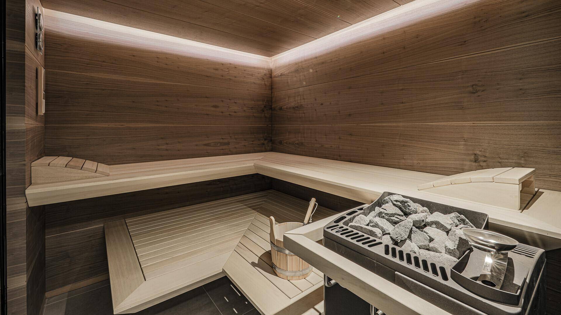 Moderne Holzsauna mit Bänken und Saunaofen für entspannende Wellnessmomente.