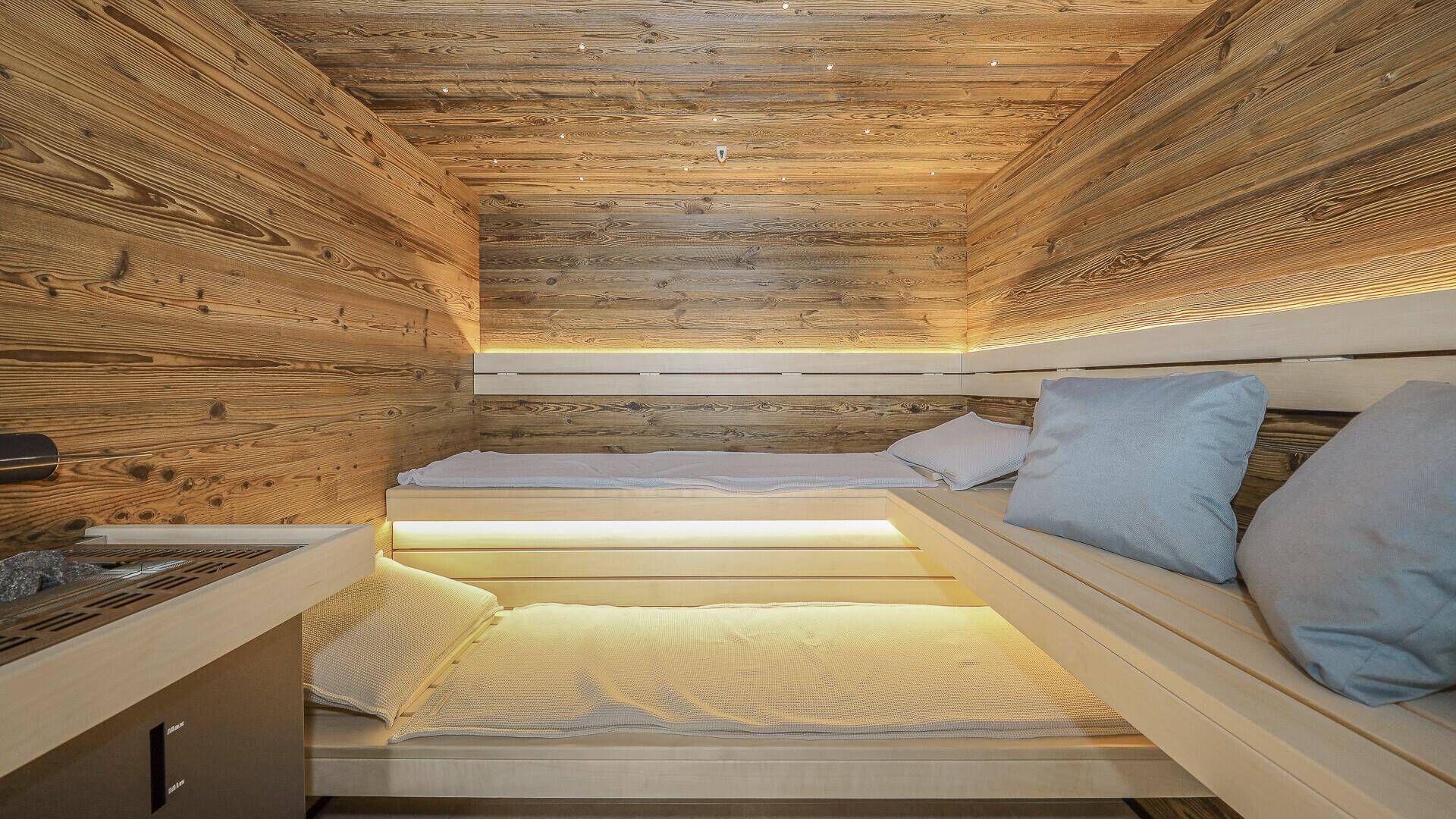 Gemütliche Holzsauna mit mehrstufigen Bänken und indirekter Beleuchtung für Entspannung.