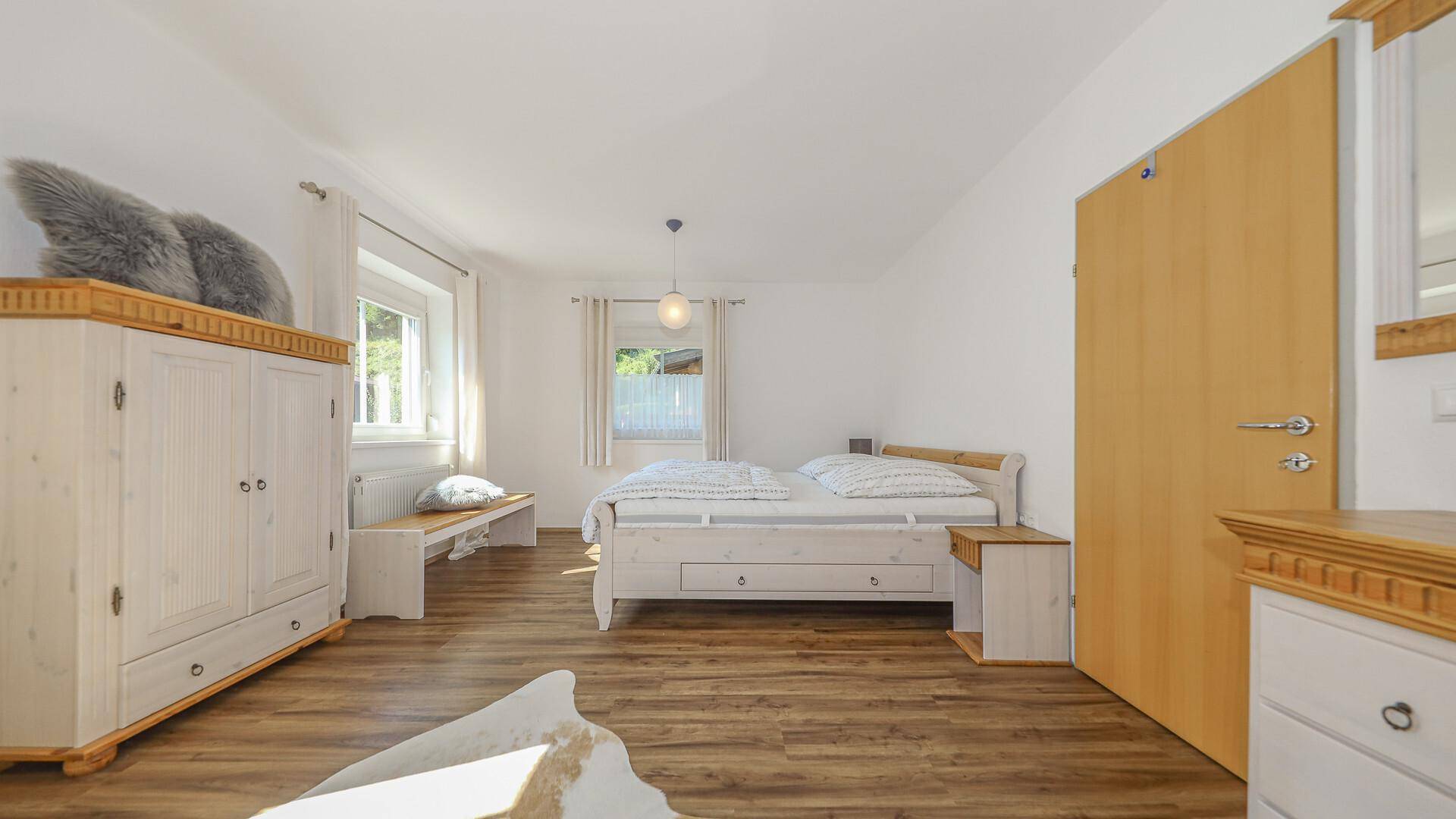 Geräumiges Schlafzimmer mit Holzboden, Fenster und viel Tageslicht.