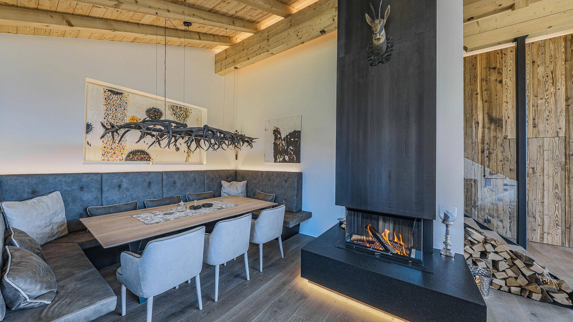 Moderner Essbereich mit integrierter Sitzbank, Kamin und Hirschgeweih-Dekoration an der Wand.