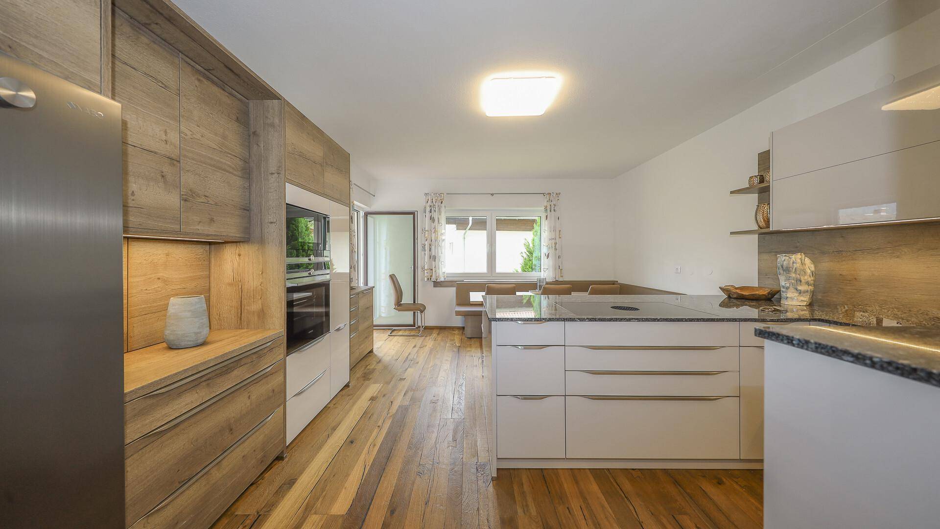 Moderne Küche mit hellen Holz- und weißen Schränken, Kochinsel und hochwertigem Holzboden.