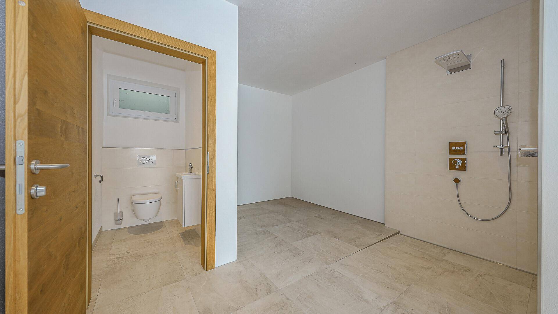 Modernes Badezimmer mit großer Dusche und separatem WC-Bereich.