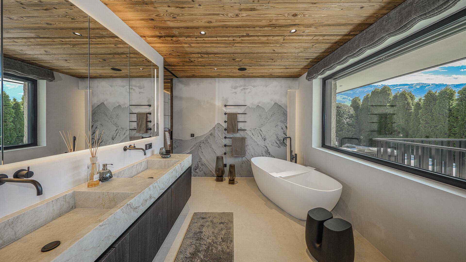 Elegantes Badezimmer mit Doppelwaschbecken, freistehender Badewanne und Blick auf die Berge.