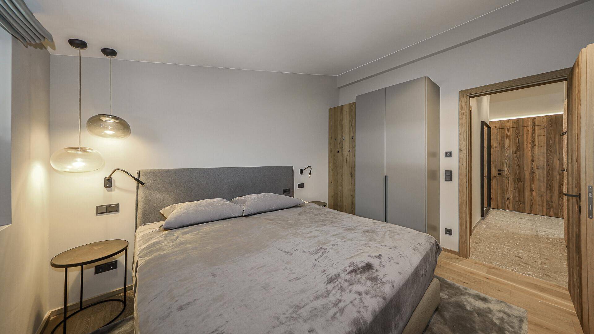 Helles Schlafzimmer mit Doppelbett, Einbauschränken und stilvoller Beleuchtung.