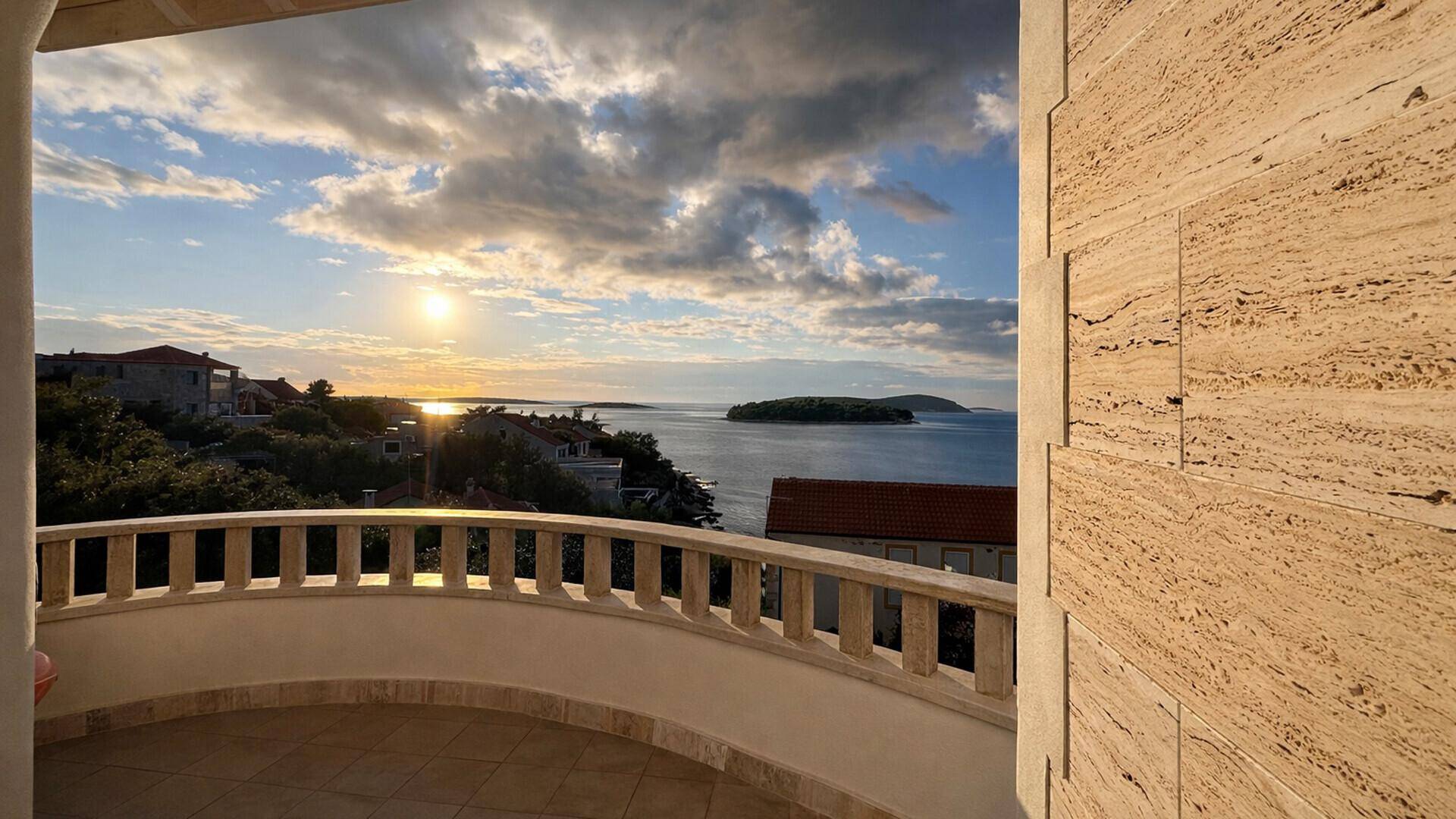 Geräumiger Balkon mit Steinbrüstung und atemberaubendem Meerblick bei Sonnenuntergang.