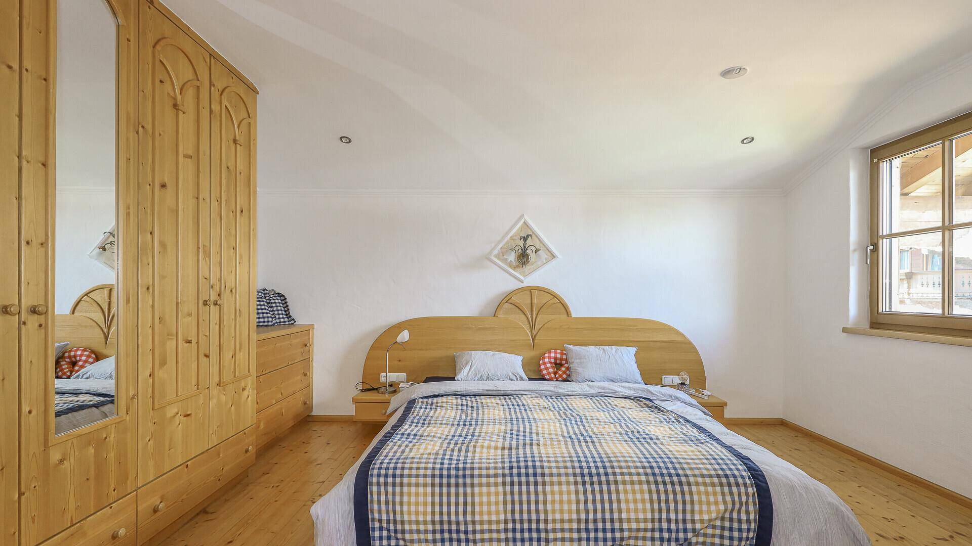 Gemütliches Schlafzimmer mit Doppelbett, Holzschrank und traditioneller Einrichtung.