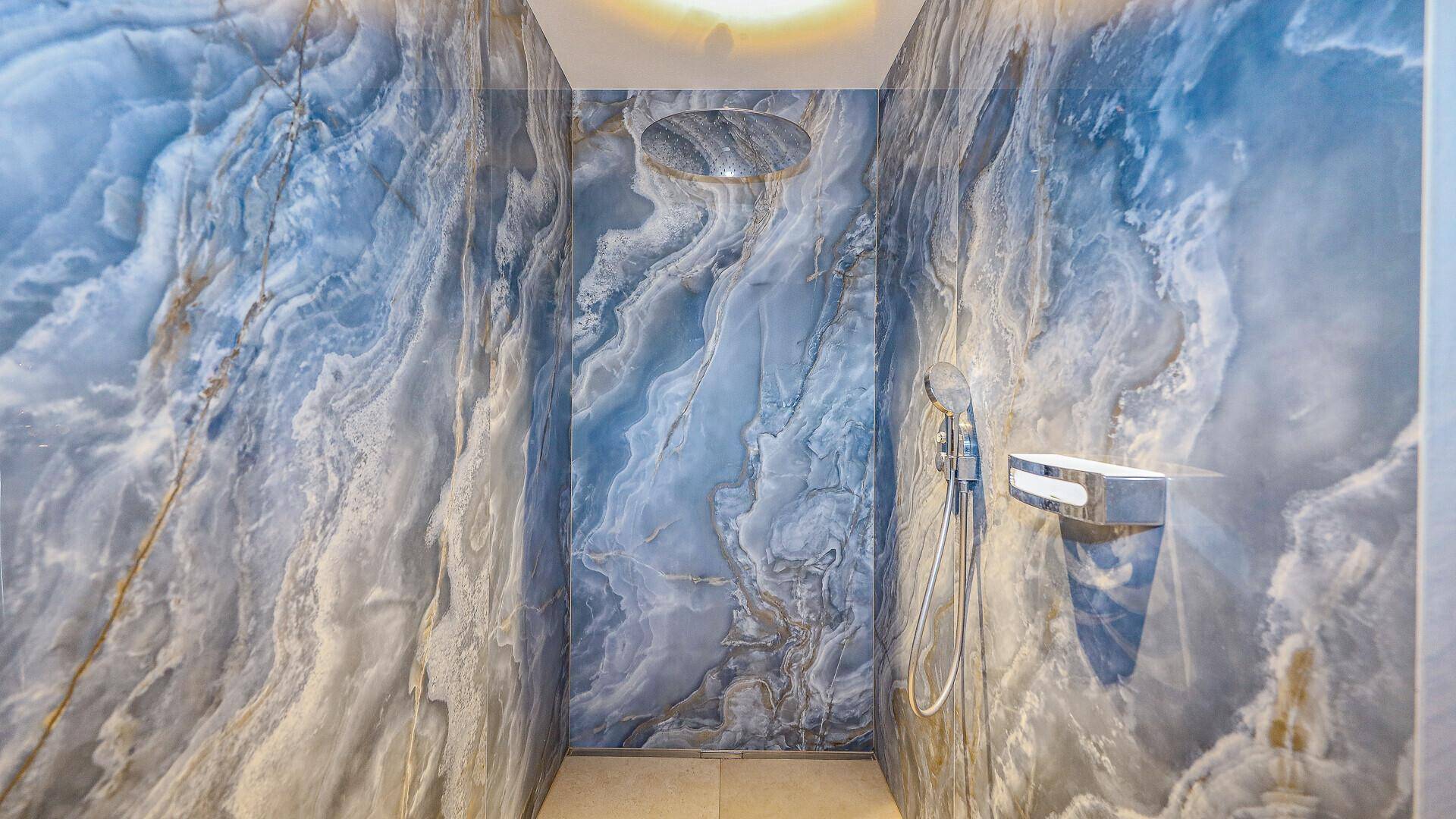 Luxuriöse Dusche mit blauen Marmorwänden und Regenduschkopf in modernem Design.