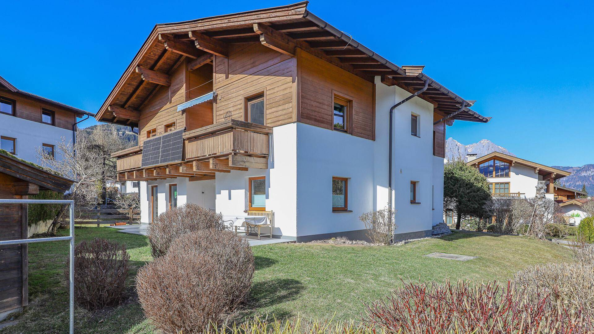 Charmantes Haus mit Holzelementen, weißer Fassade und Bergblick in ländlicher Umgebung.