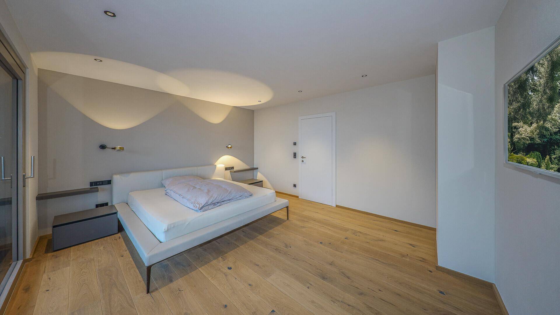 Modernes Schlafzimmer mit Holzboden, indirekter Beleuchtung und minimalistischem Design.