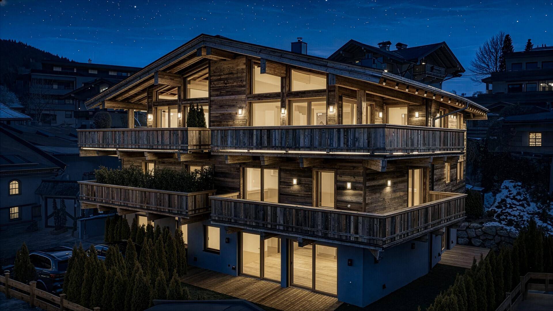 Beeindruckendes Chalet im alpinen Stil bei Nacht mit beleuchteten Balkonen.