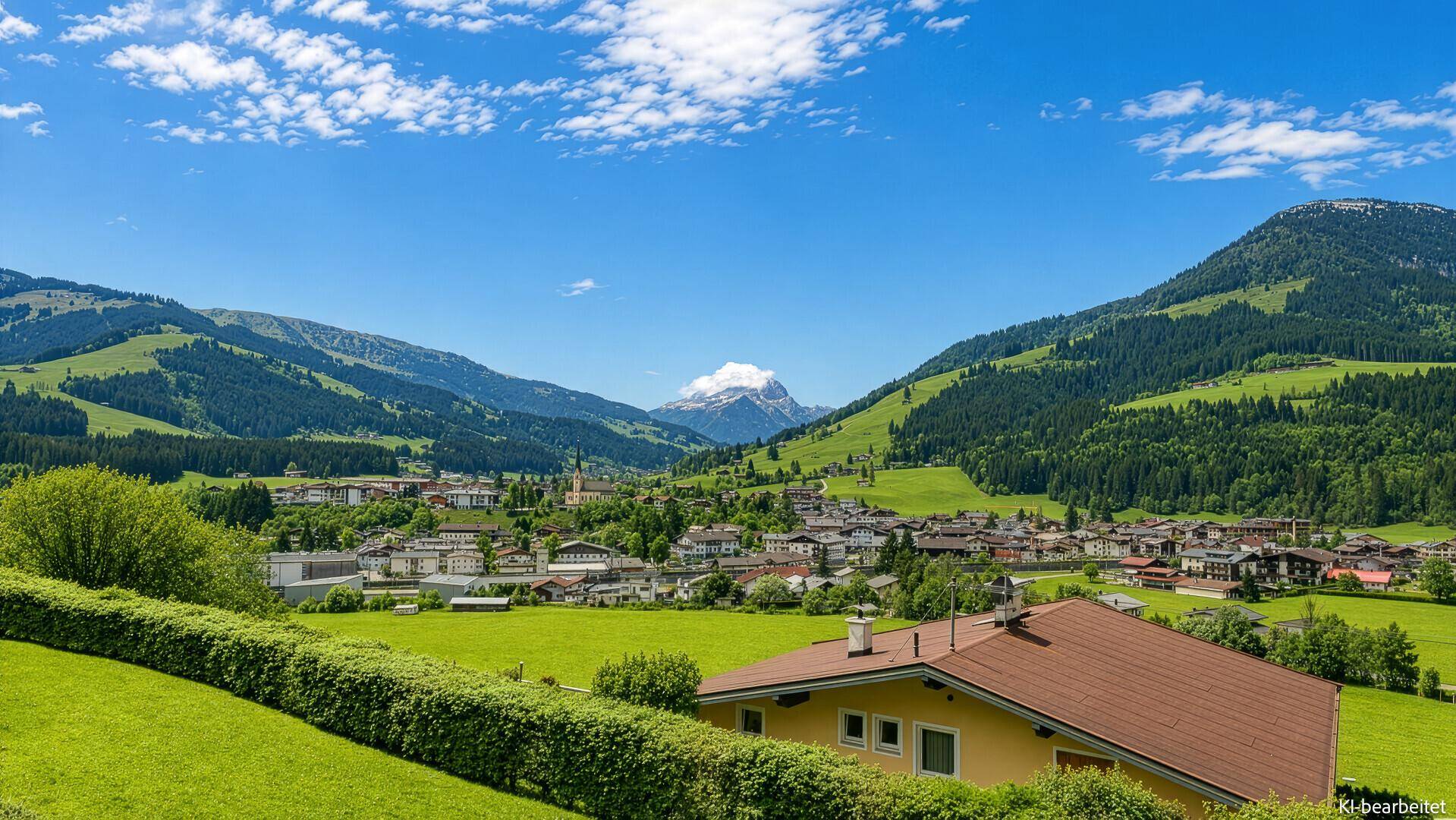Weitläufiger Panoramablick auf ein idyllisches Dorf und die majestätische Berglandschaft.