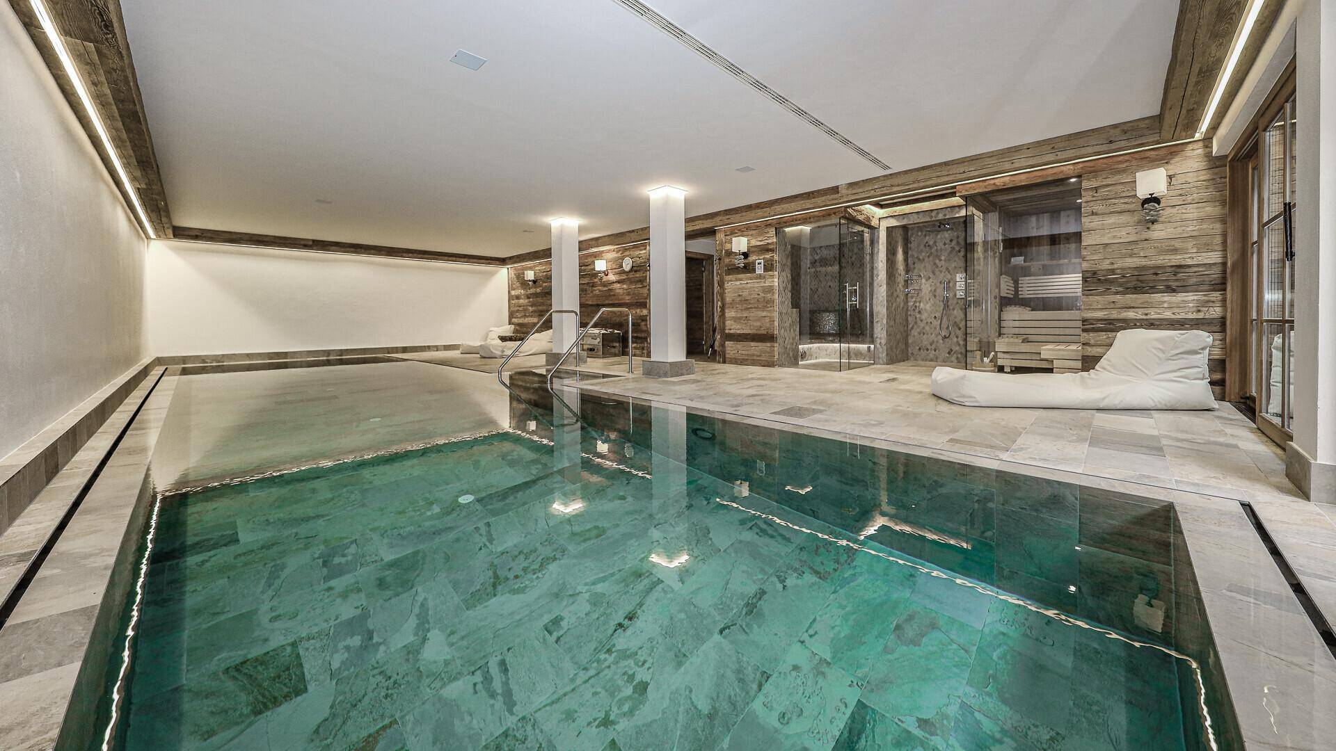 Innenpoolbereich mit Entspannungsliegen und Zugang zu Sauna und Dampfbad.