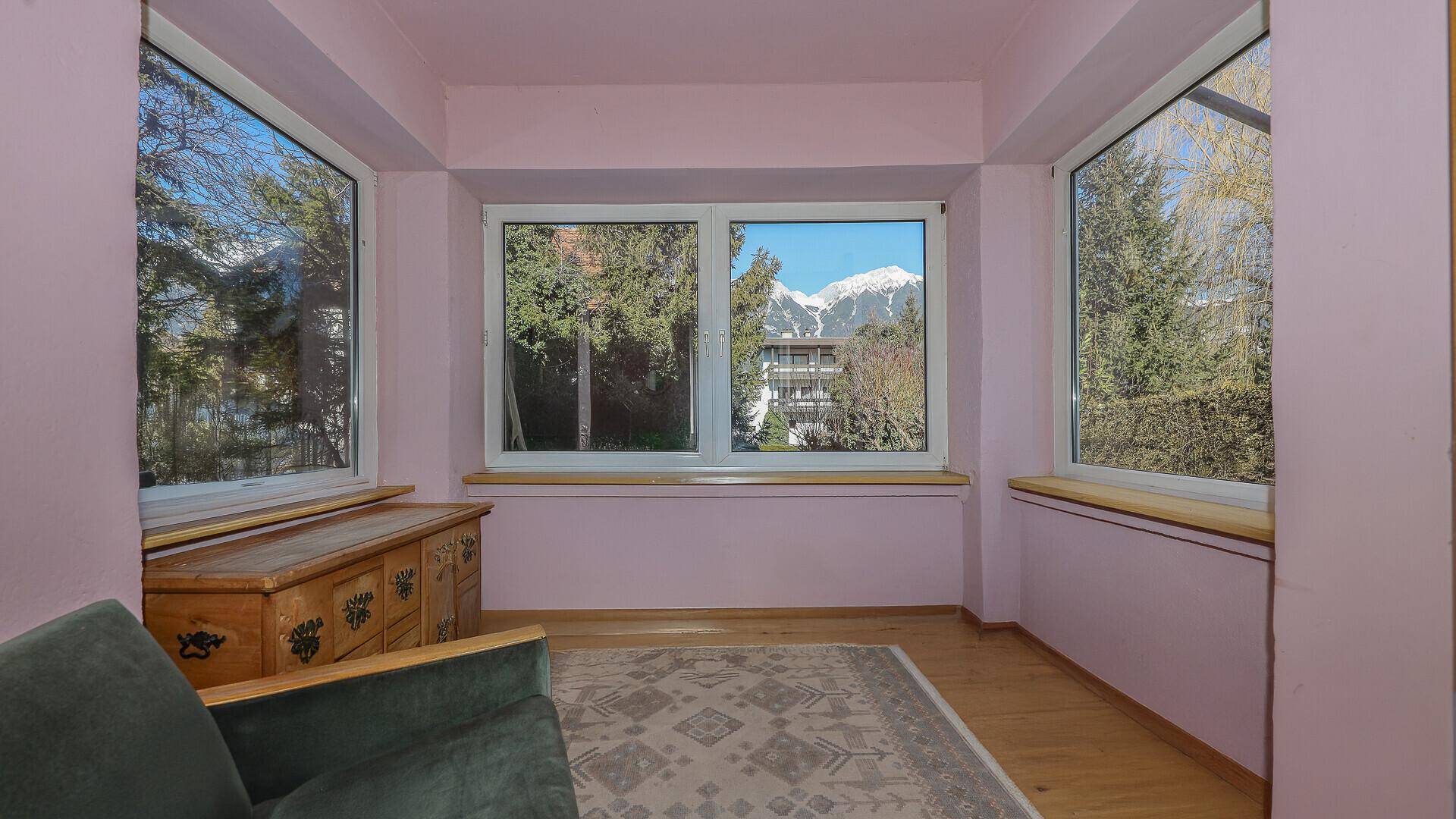 Helles Zimmer mit rosa Wänden, Holzboden und beeindruckendem Bergblick.