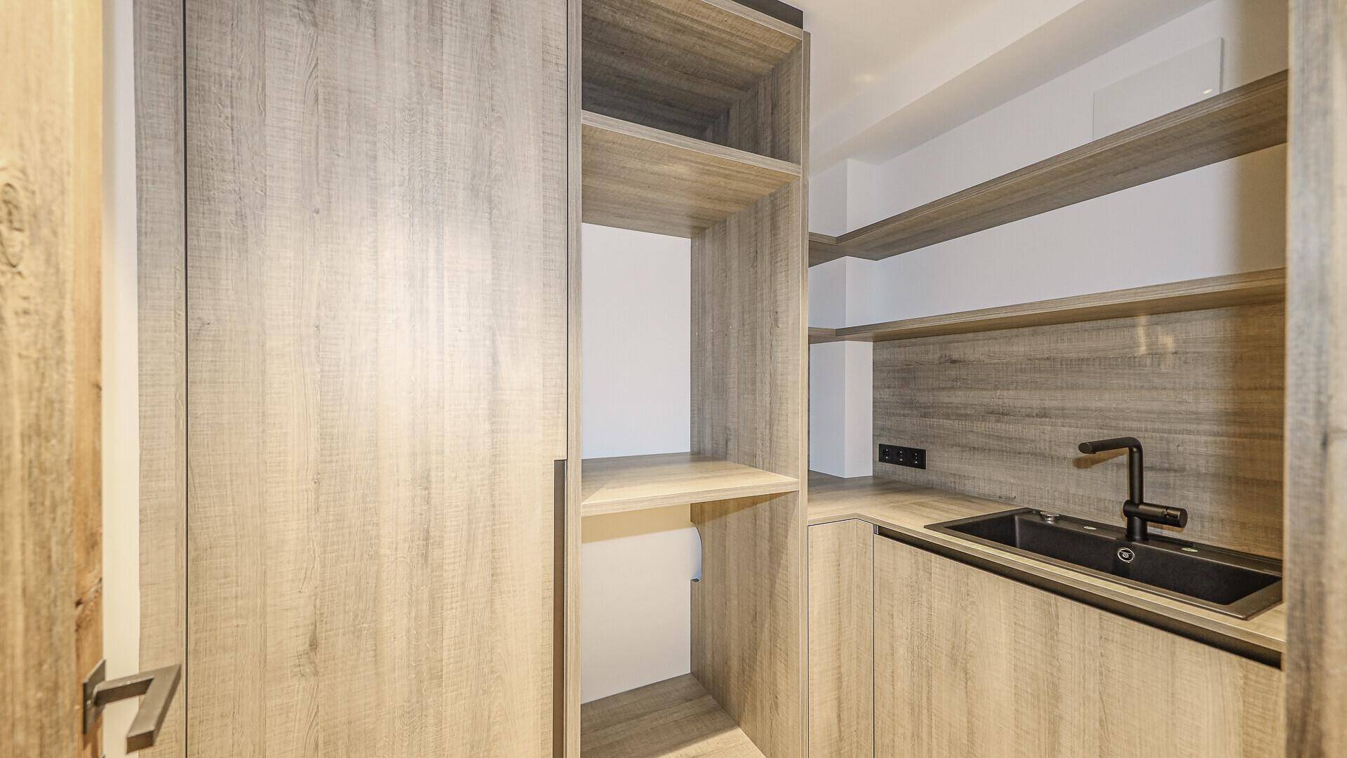 Kleine Küchenzeile oder Hauswirtschaftsraum mit Spüle und Holzschränken.