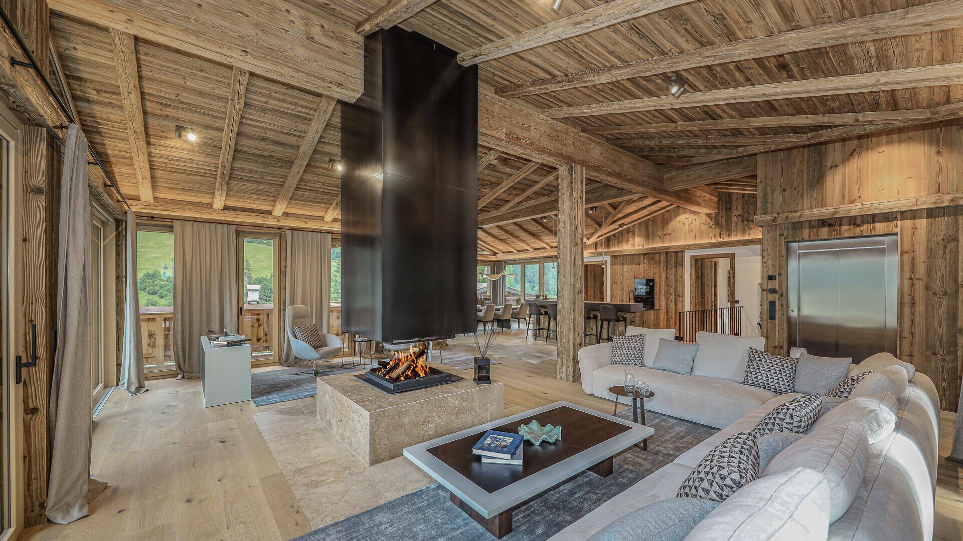 Gemütliches Wohnzimmer im alpinen Stil mit Holzbalkendecke, Kamin und bequemen Sofas.