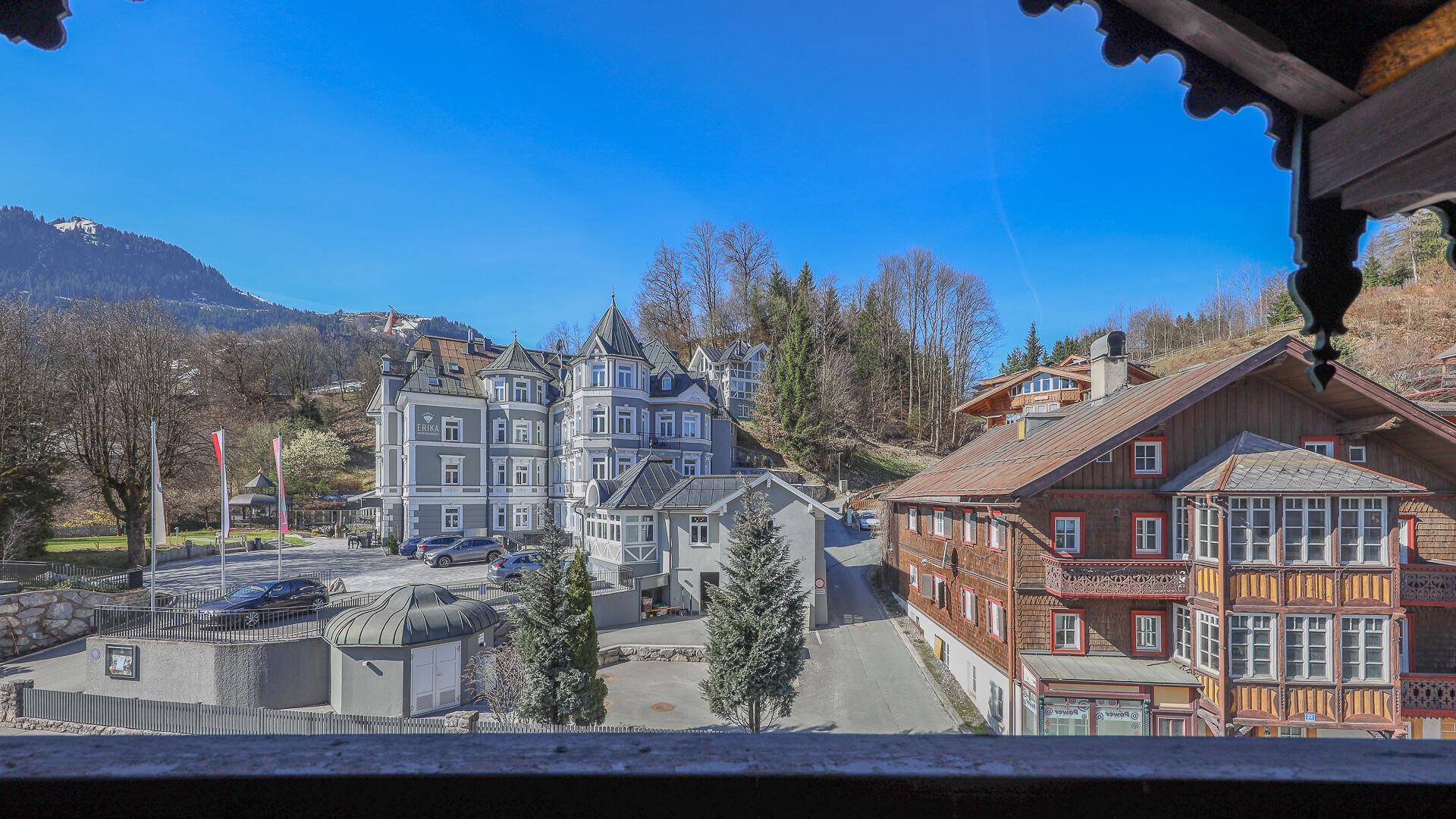 Blick von einem Balkon auf die umliegenden Gebäude im traditionellen Stil und die dahinterliegende Berglandschaft.