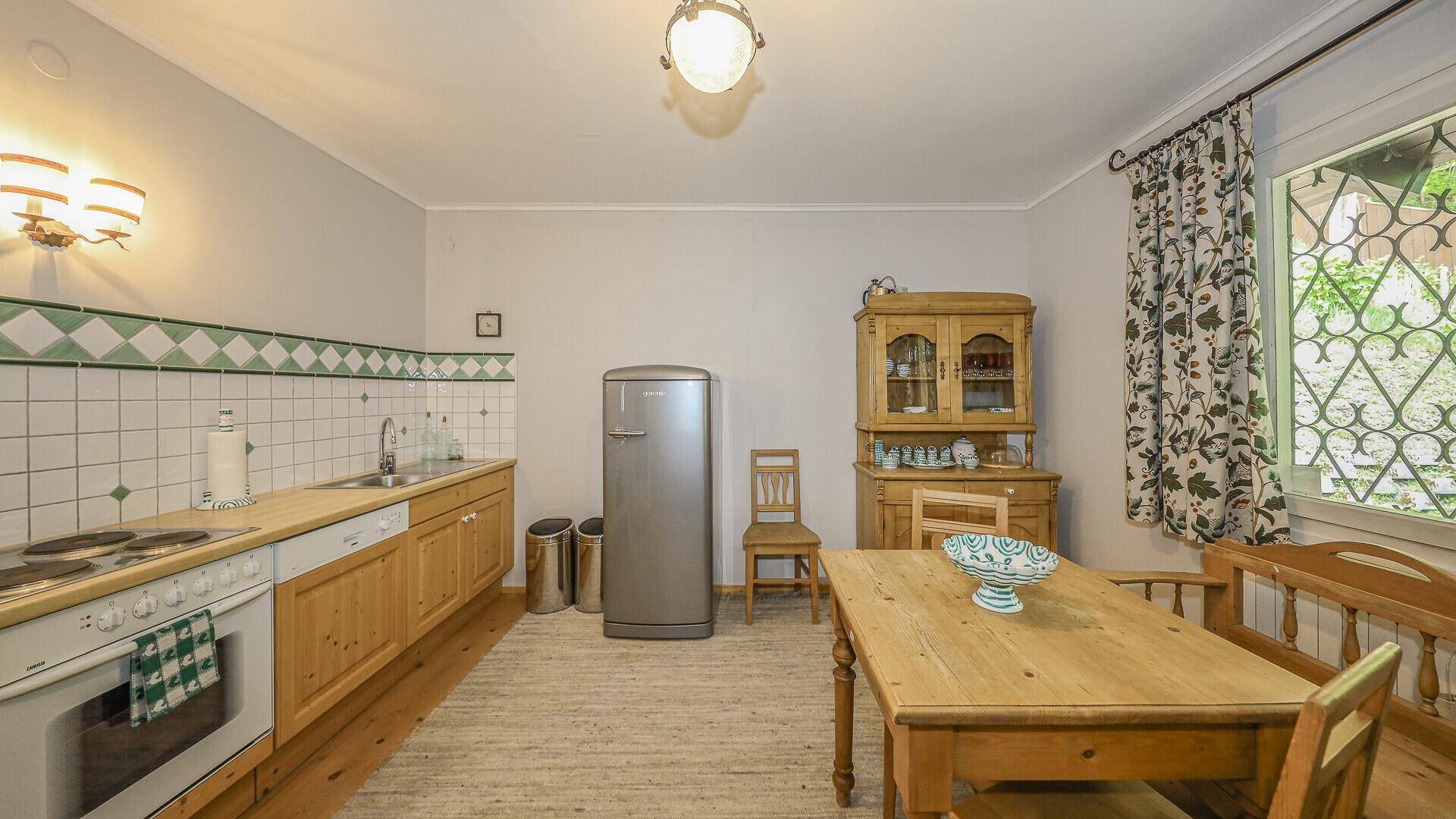 Gemütliche Küche mit Essbereich, Holzmöbeln, traditionellen Fliesen und Fenster.