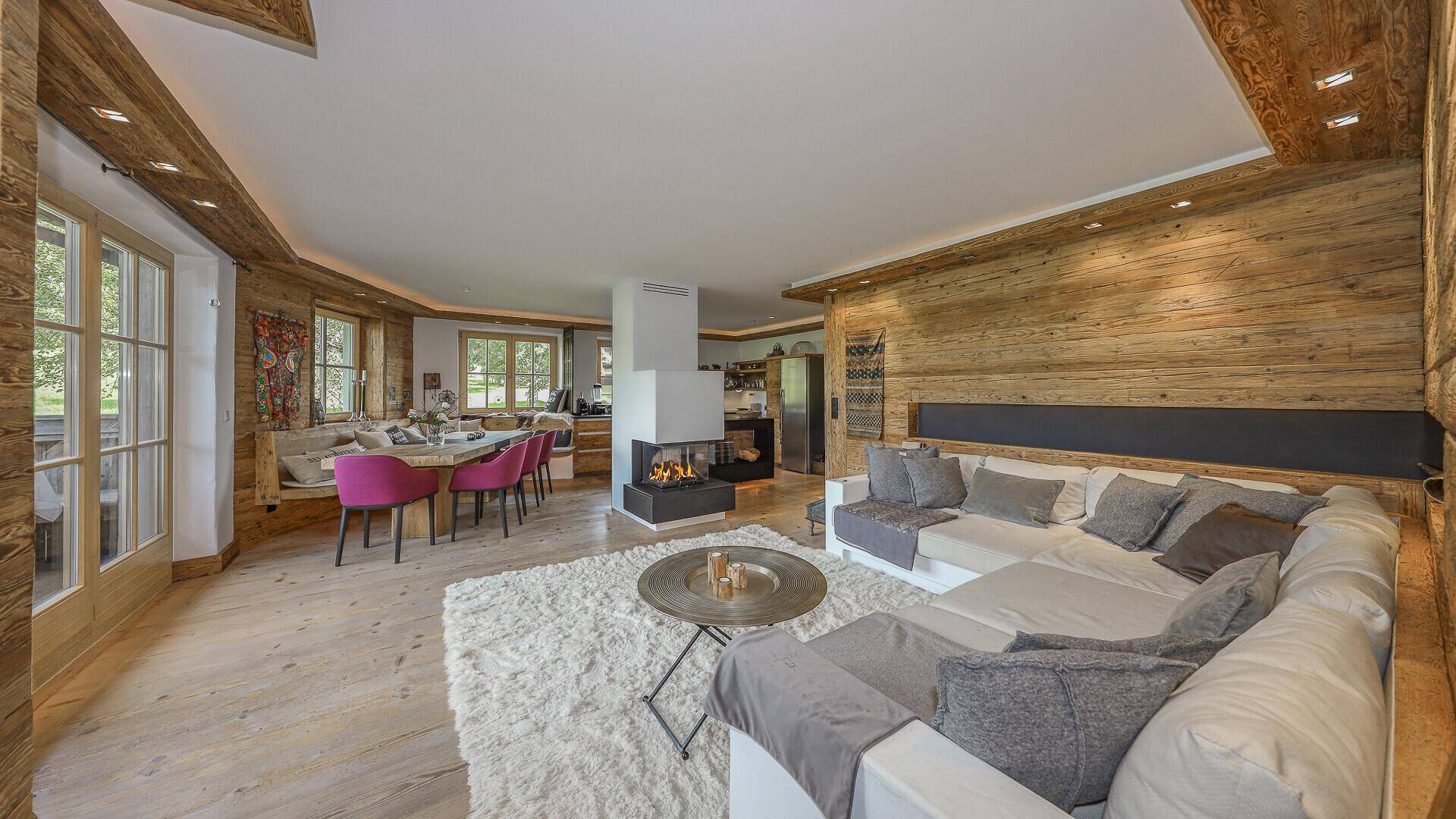Heller Wohn- und Essbereich mit Holzwänden, Kamin und gemütlicher Sitzecke im Landhausstil.